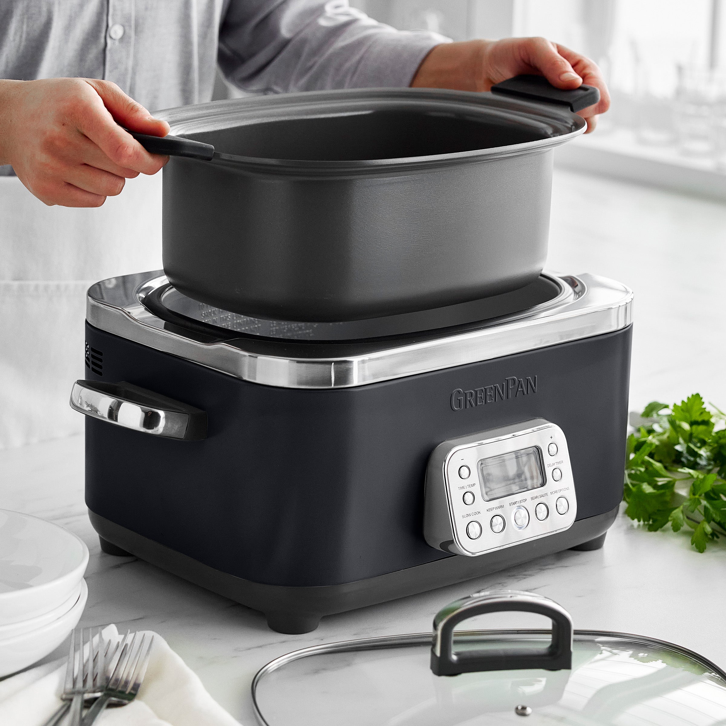 Person removing a pot from a slow cooker