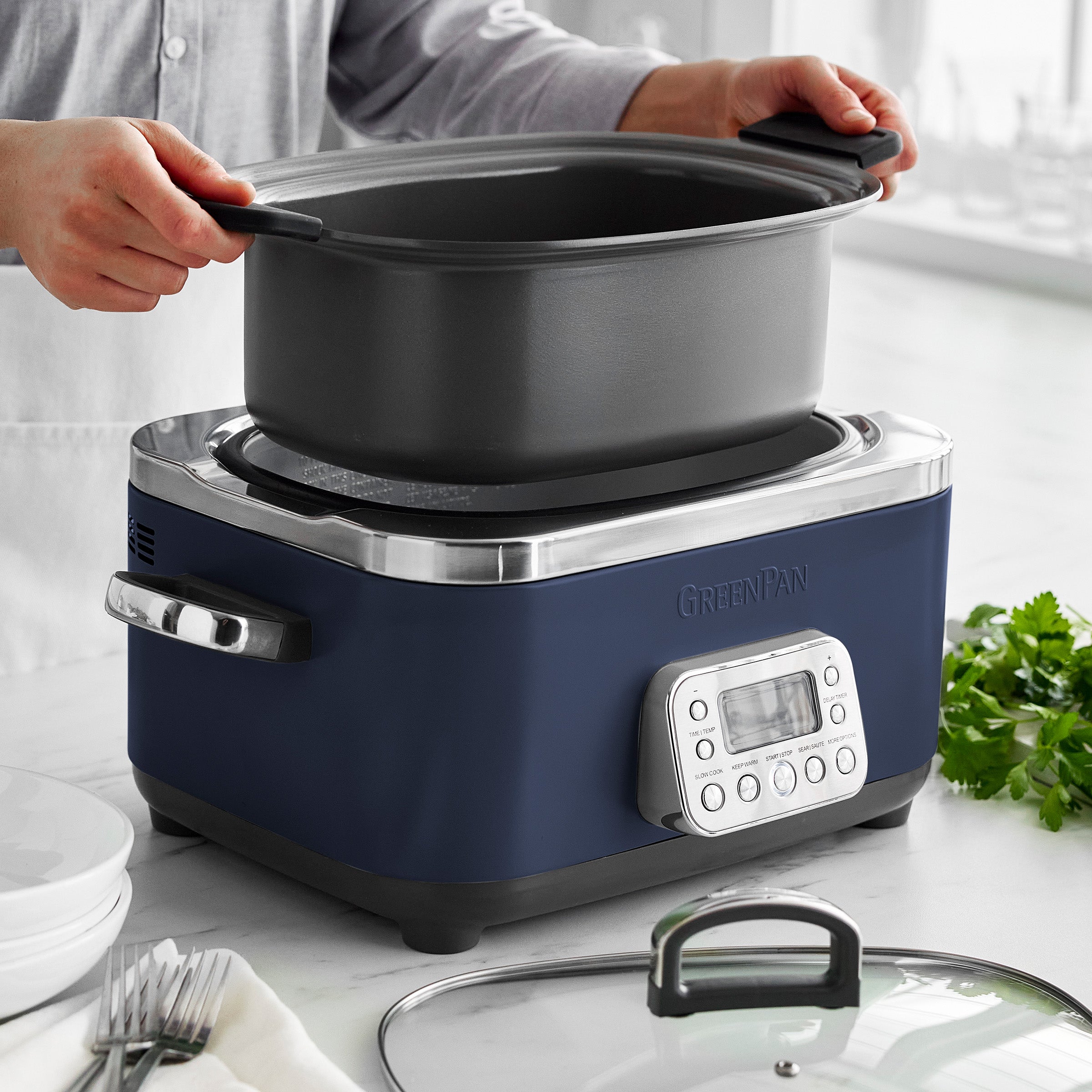 Person removing a pot from a slow cooker