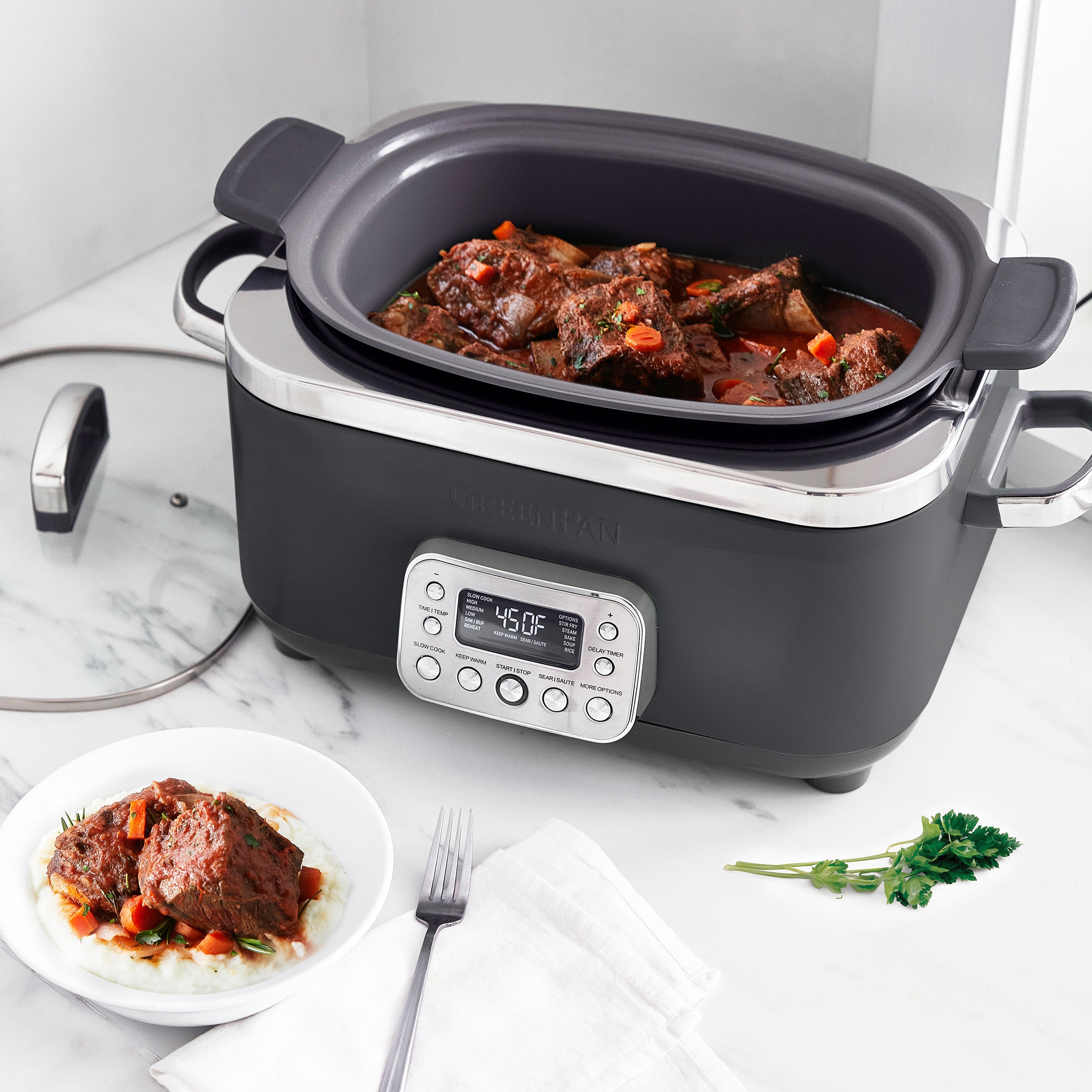 Gray slow cooker with digital display on a marble countertop, containing stewed meat and vegetables.
