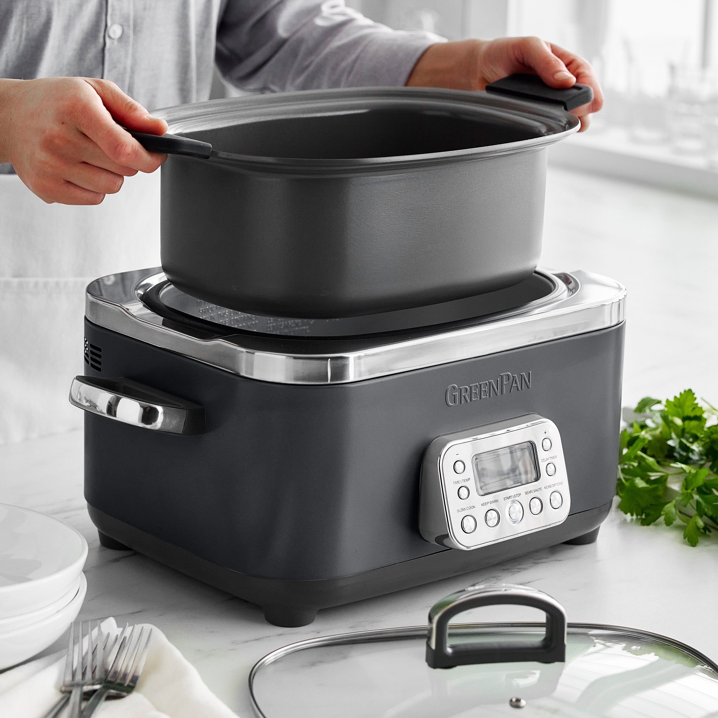 Person removing a pot from a slow cooker