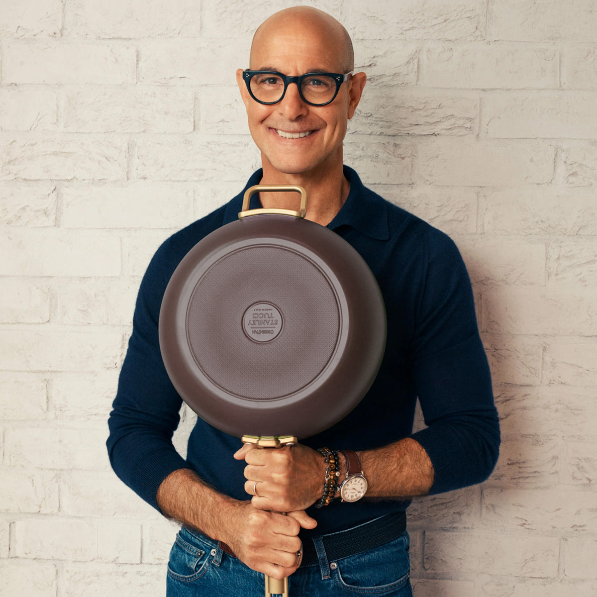 Stanley Tucci holding an espresso 6.5-quart ceramic nonstick Essential pan with gold-tone handles.