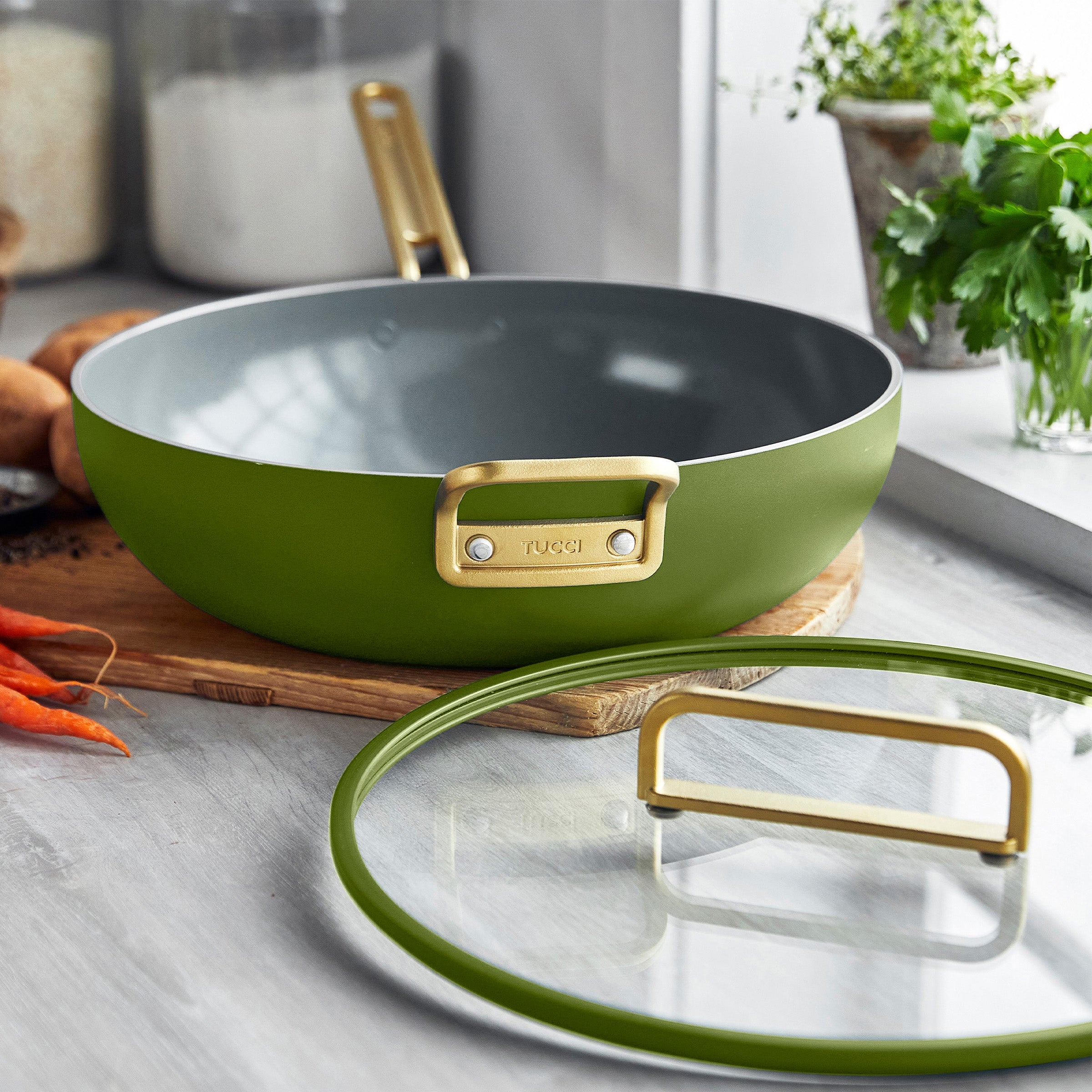 Green saute pan with gold handle on a kitchen counter