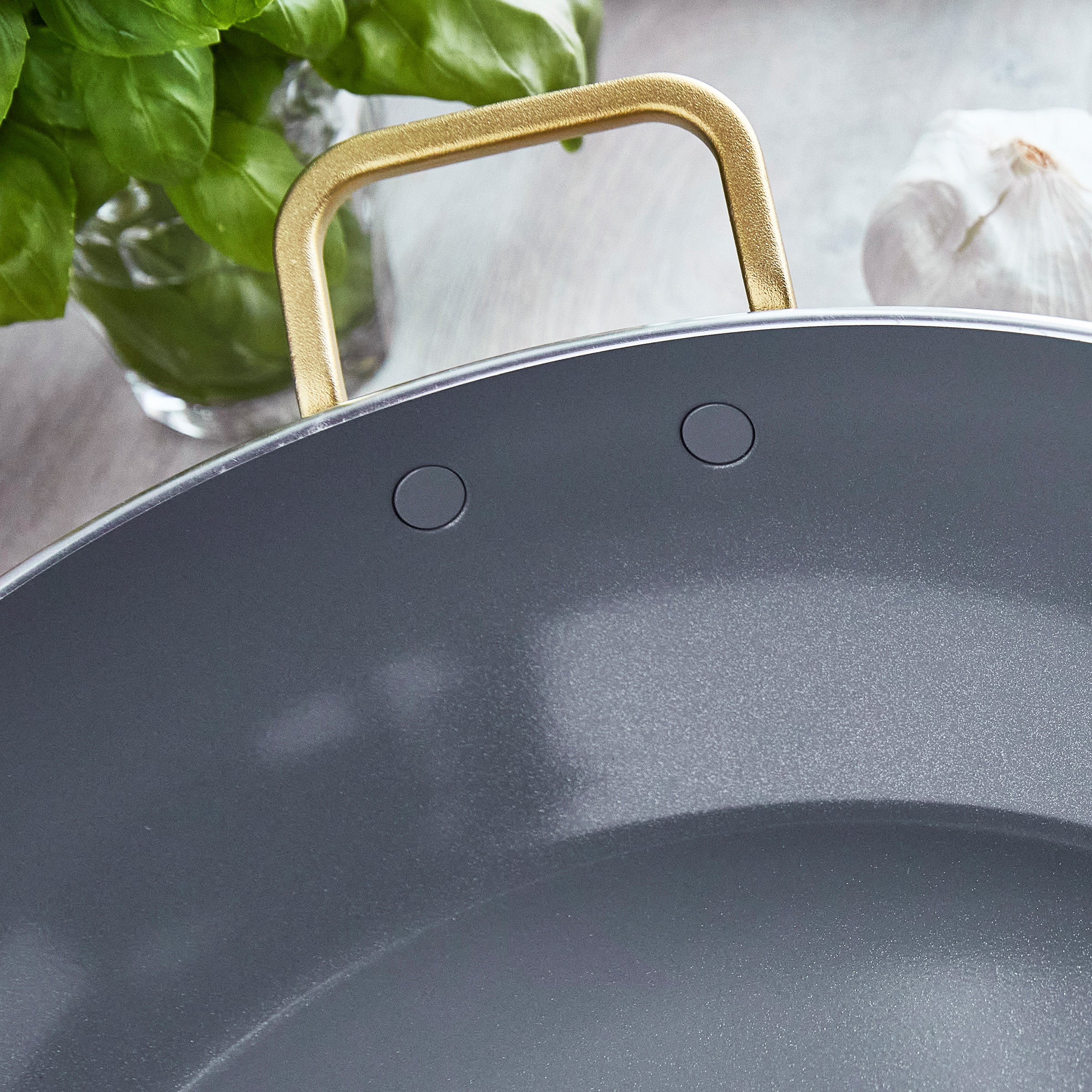Close-up of a saute pan with a gold handle on a kitchen counter.