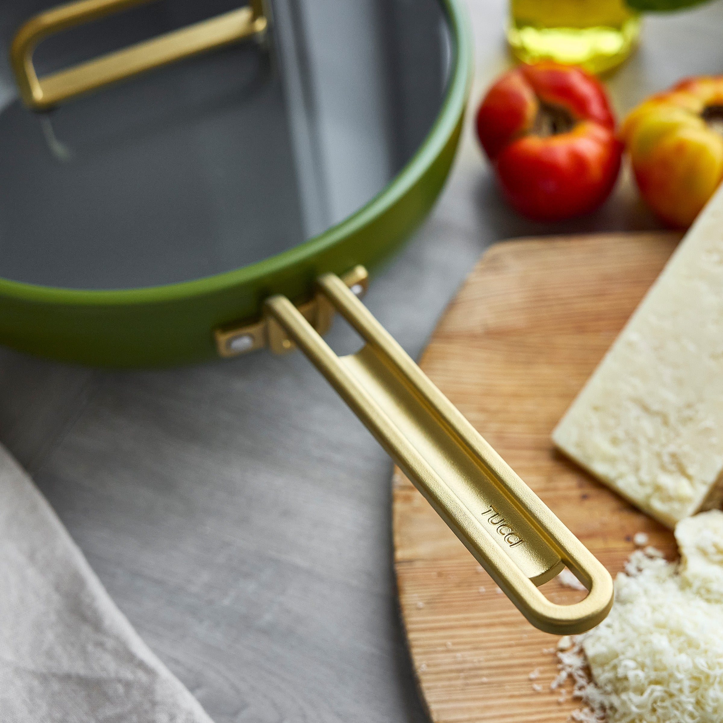 Green saute pan with a gold handle on a kitchen counter with ingredients