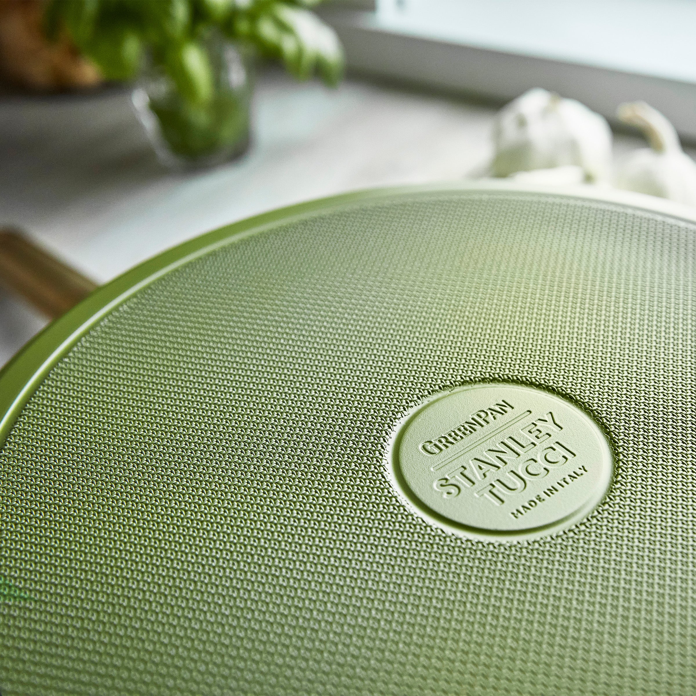Green saute pan with a brand logo on a kitchen counter