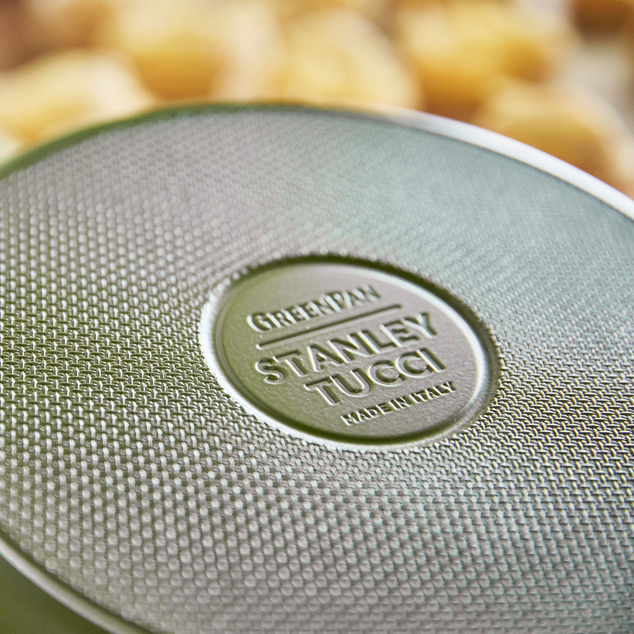 Close-up of a green frypan with 'Stanley Tucci' branding.