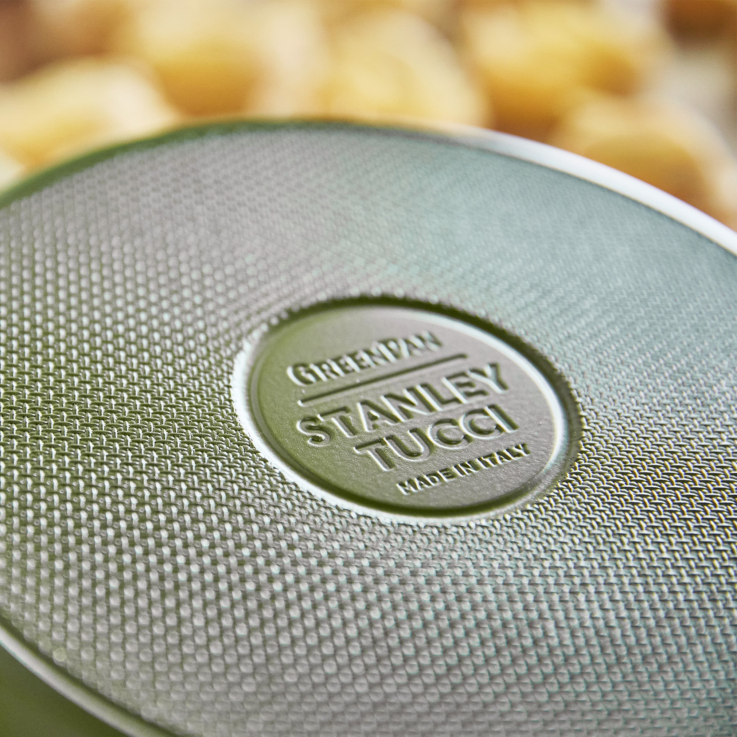 Close-up of a green frypan with 'Stanley Tucci' branding.