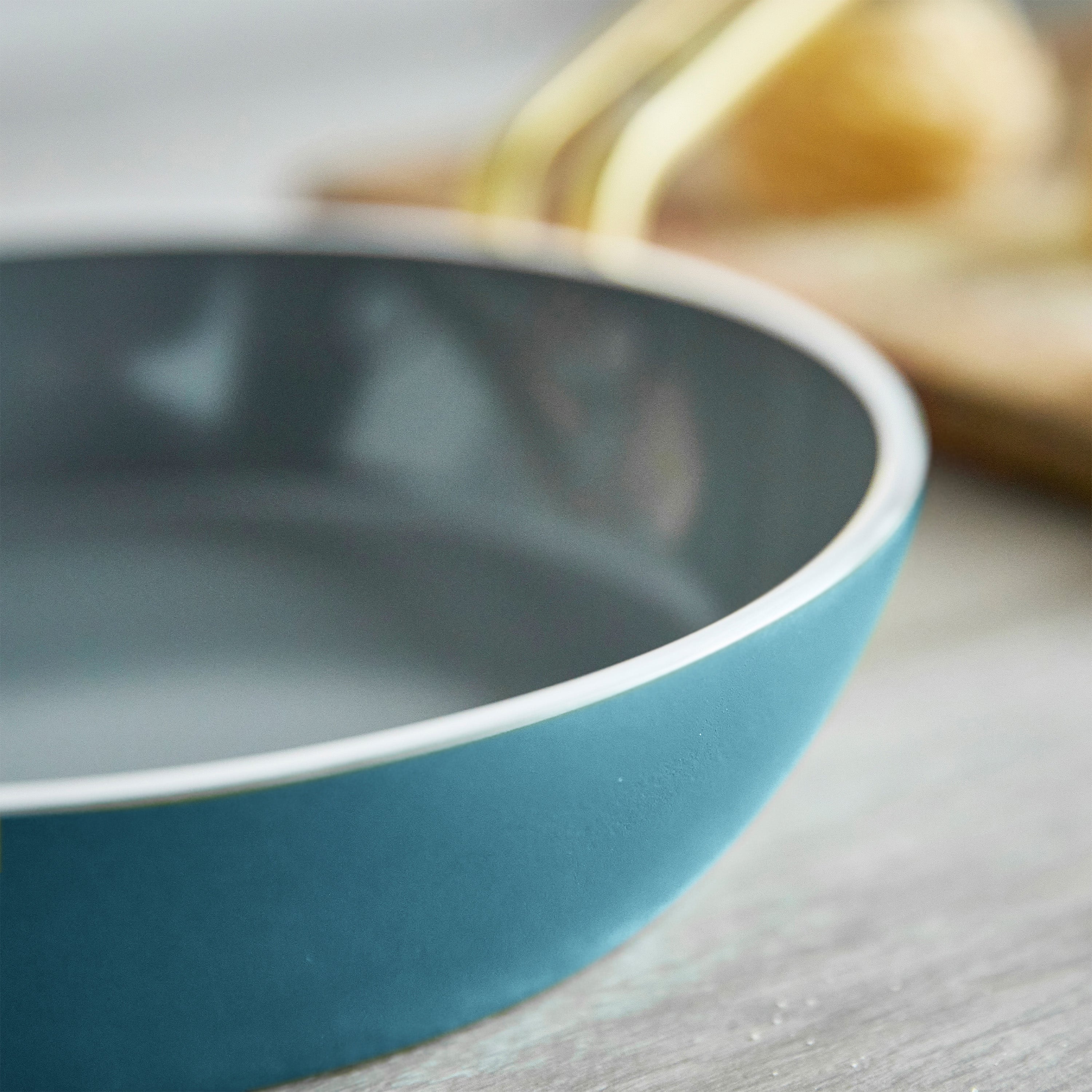 Close-up of a teal frypan on a wooden surface
