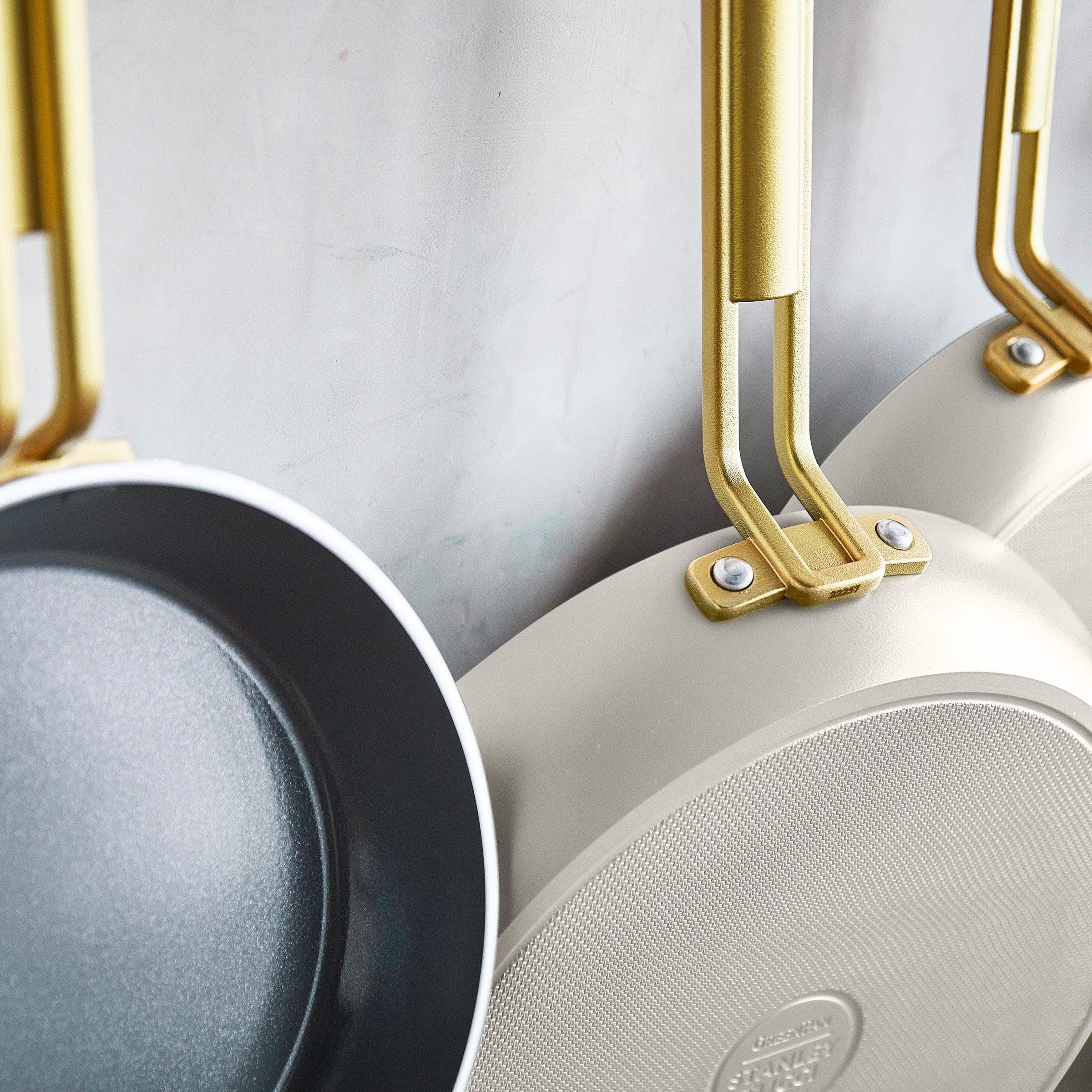 Set of white frying pans with gold handles on a light gray background