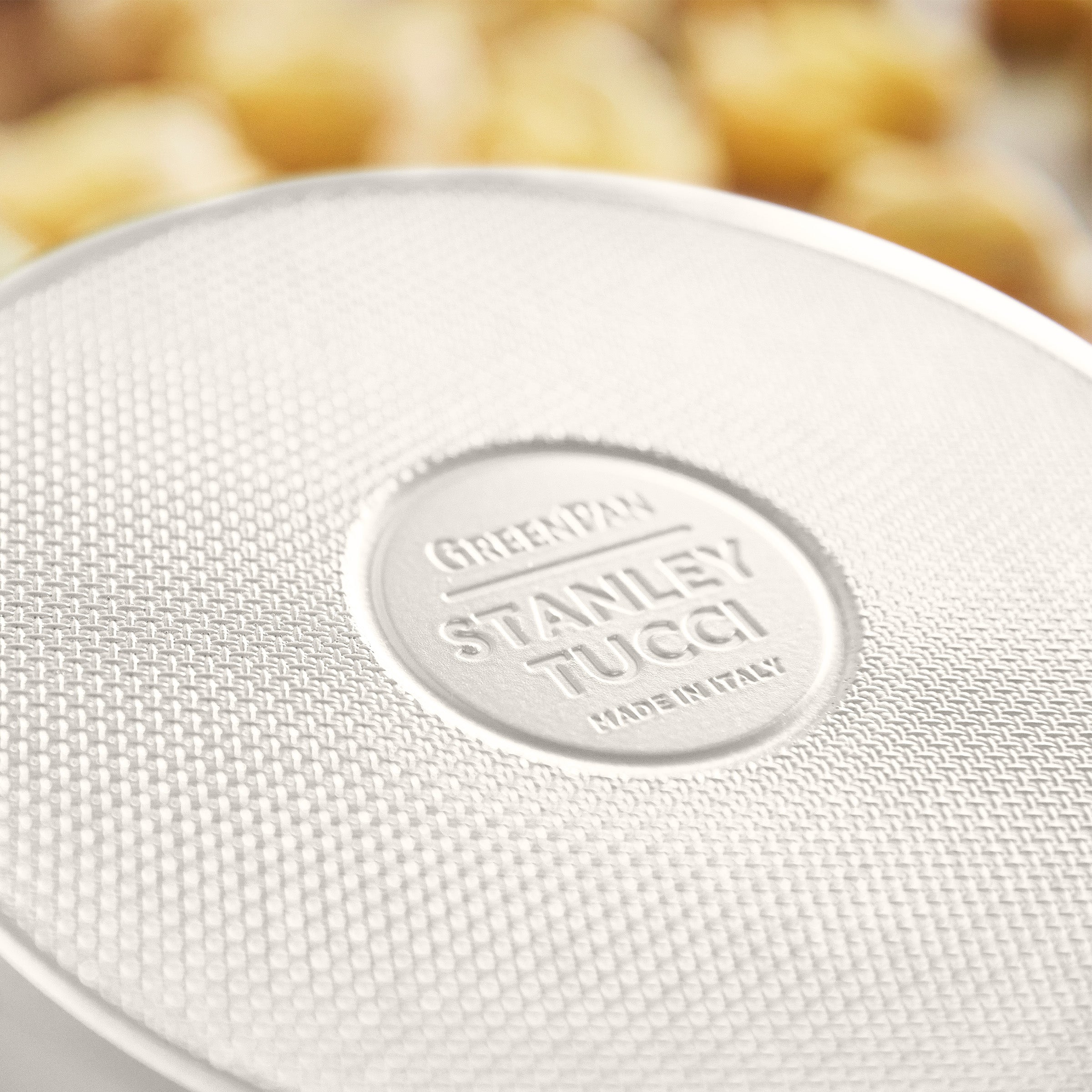 Close-up of a white frypan with 'Stanley Tucci' branding.