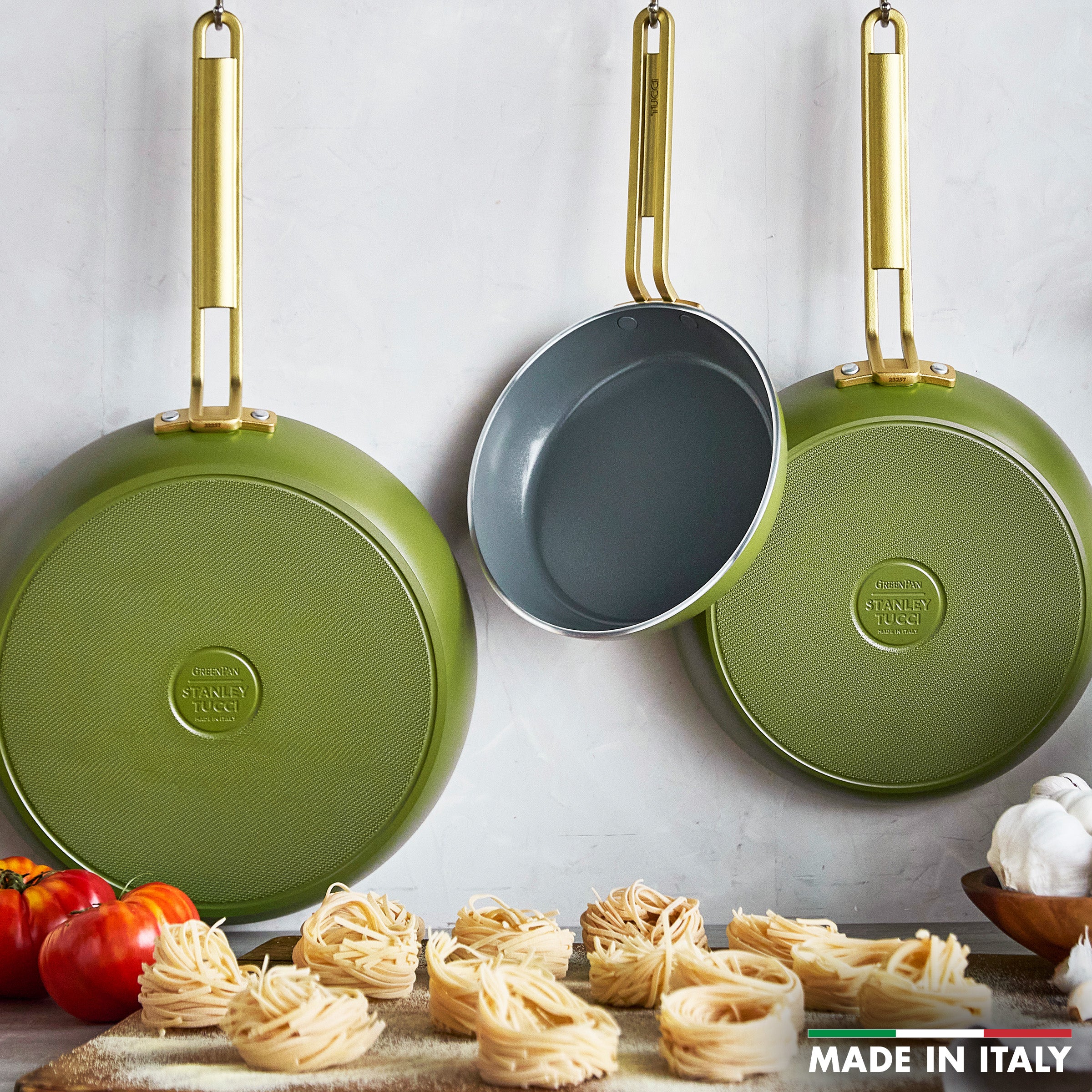 Three green frypans with gold handles, displayed against a light background.