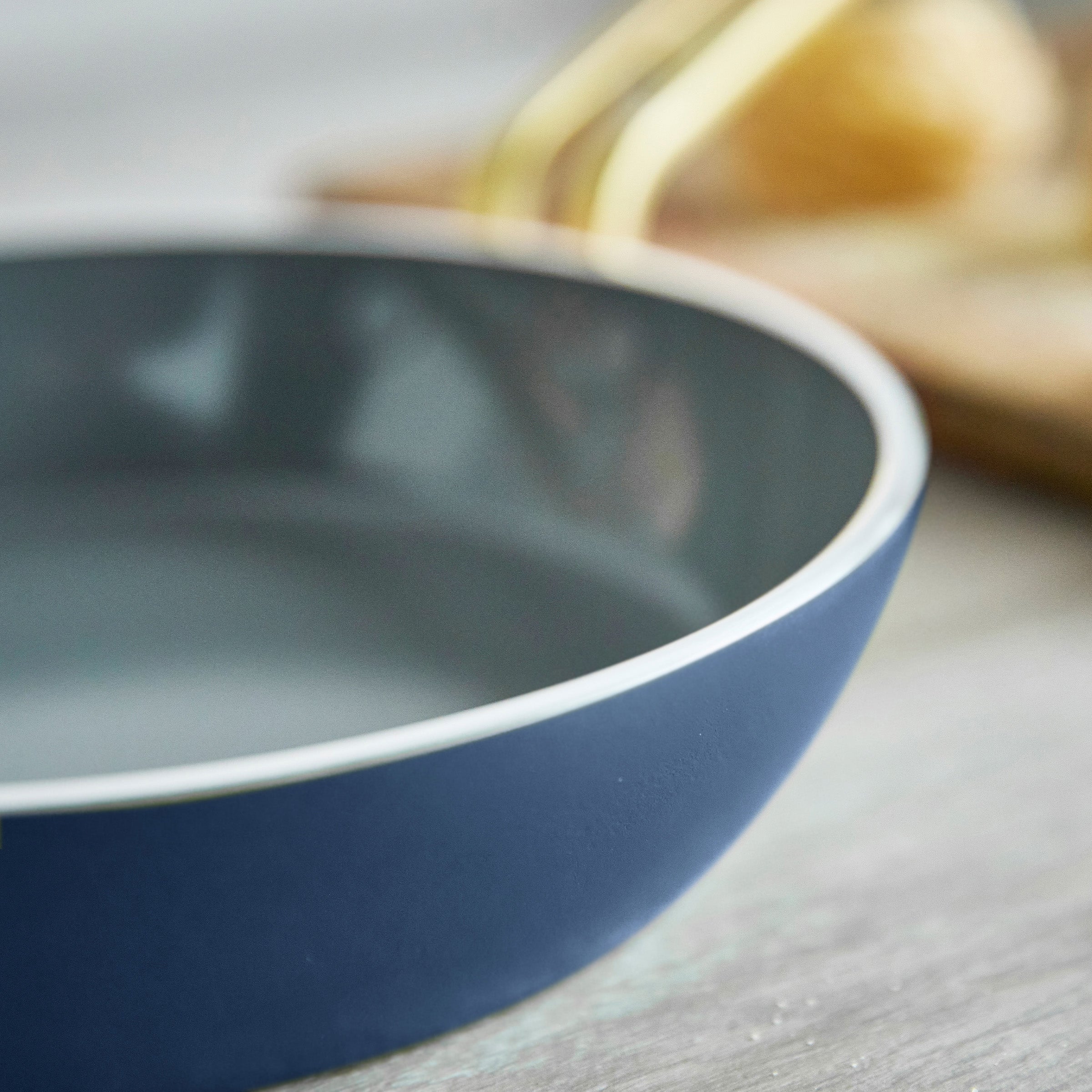 Blue frypan on a wooden surface with a blurred background
