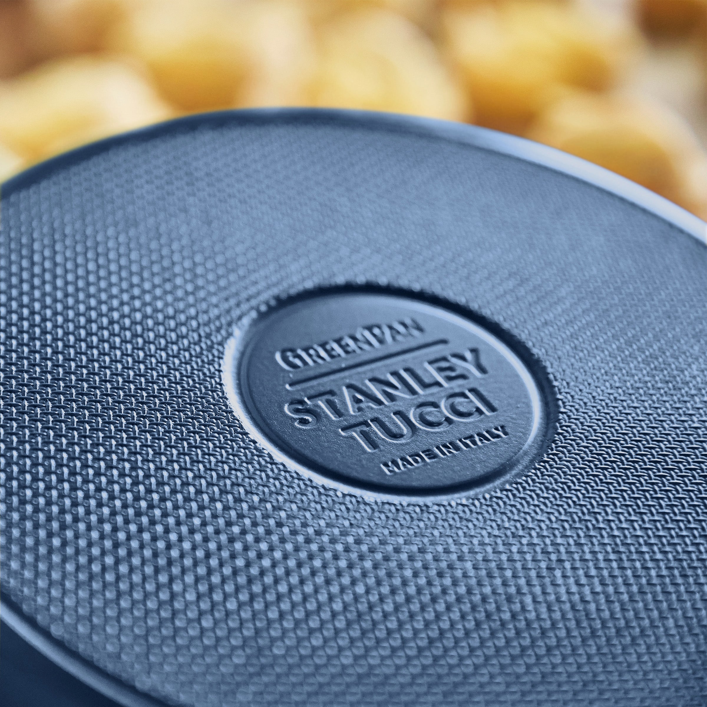 Close-up of a blue frypan with 'Stanley Tucci' branding.