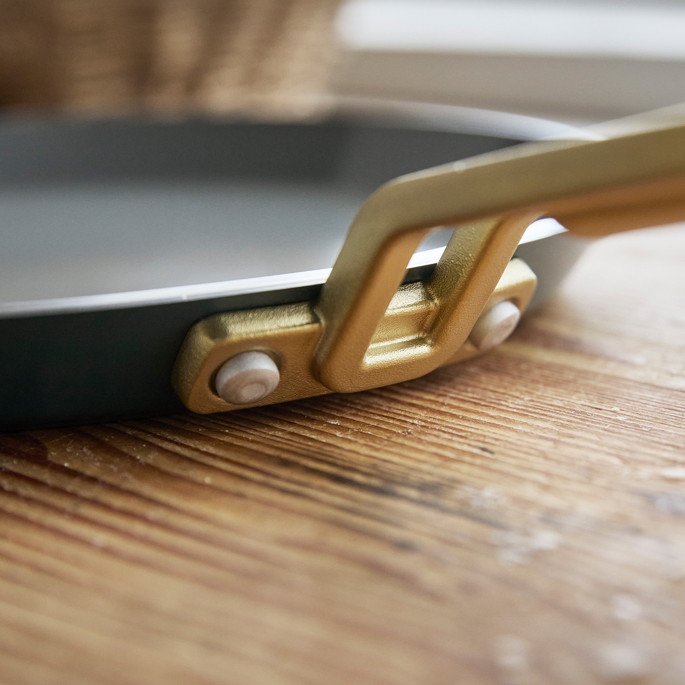 Close-up of a crepe pan with a gold handle on a wooden surface