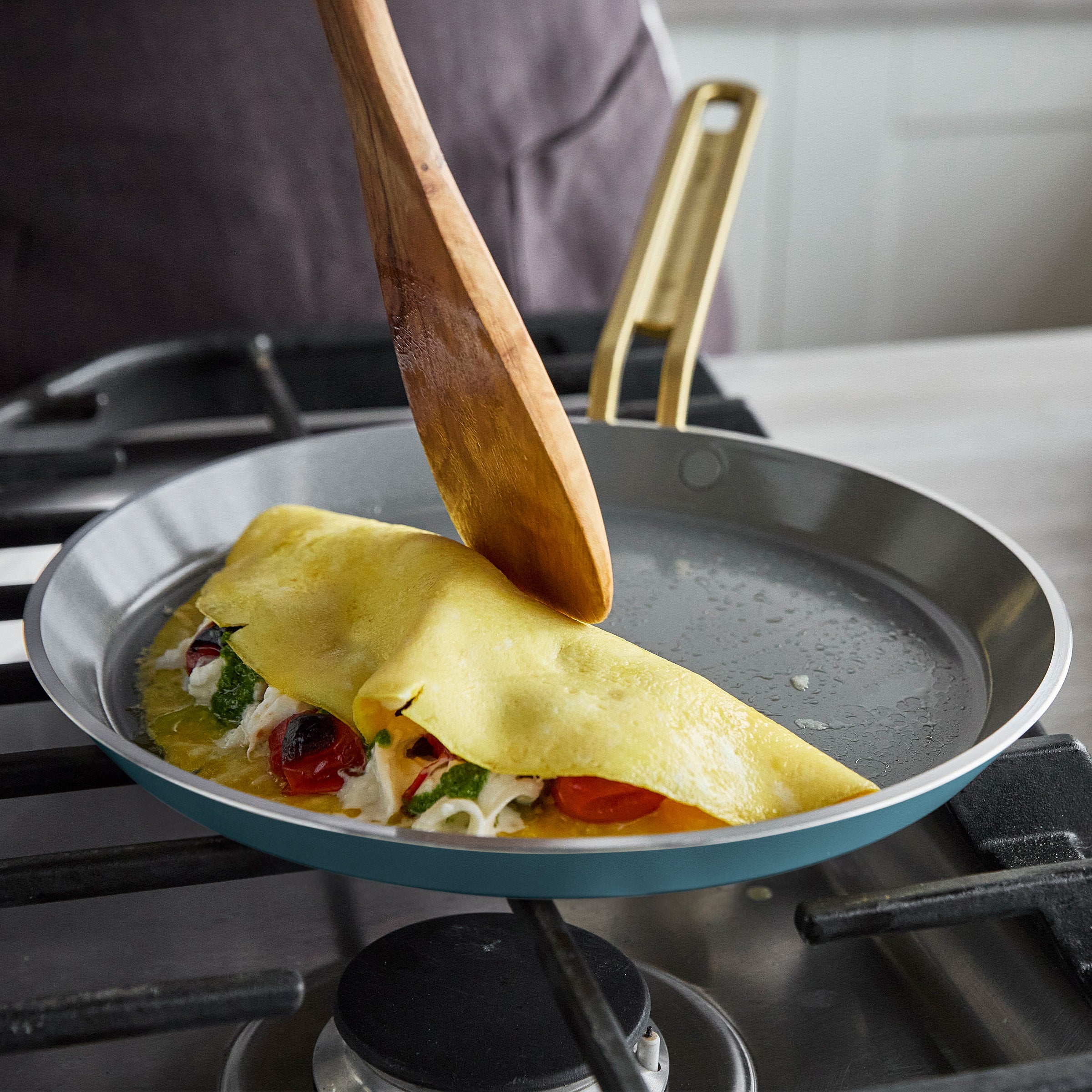 Crepe being folded in a pan with a wooden spatula