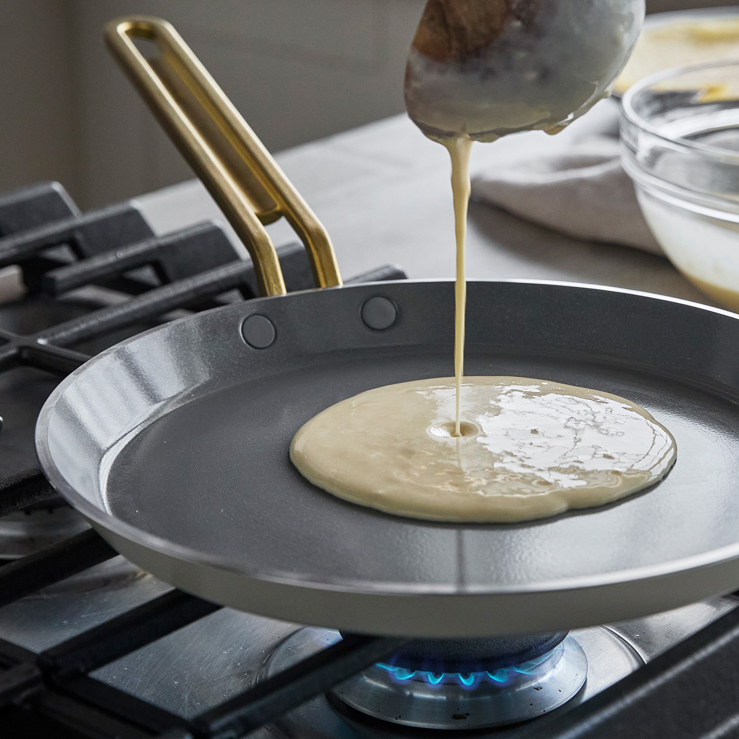 Batter being poured onto a crepe pan on a stovetop