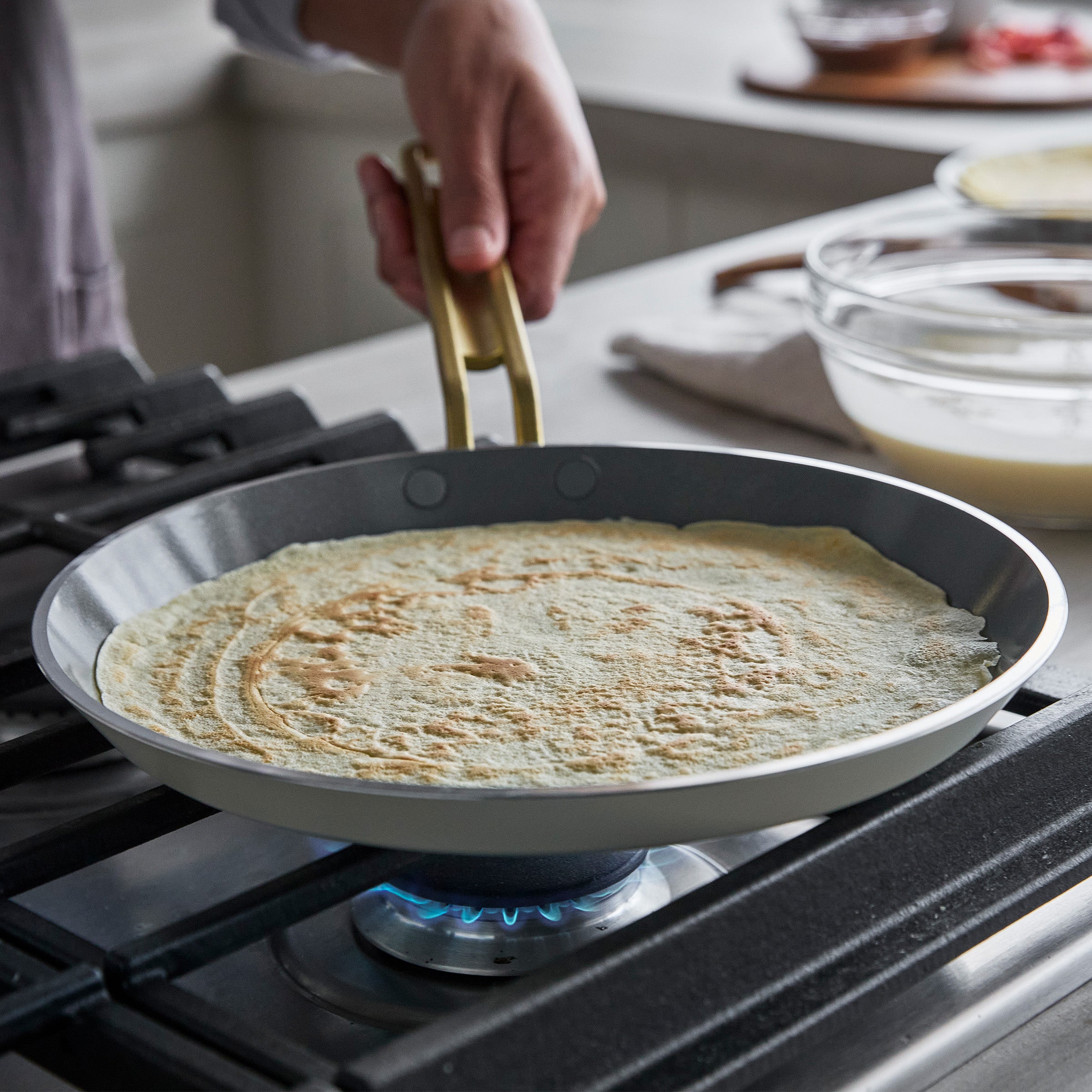 Person cooking a crepe in a pan on a stove