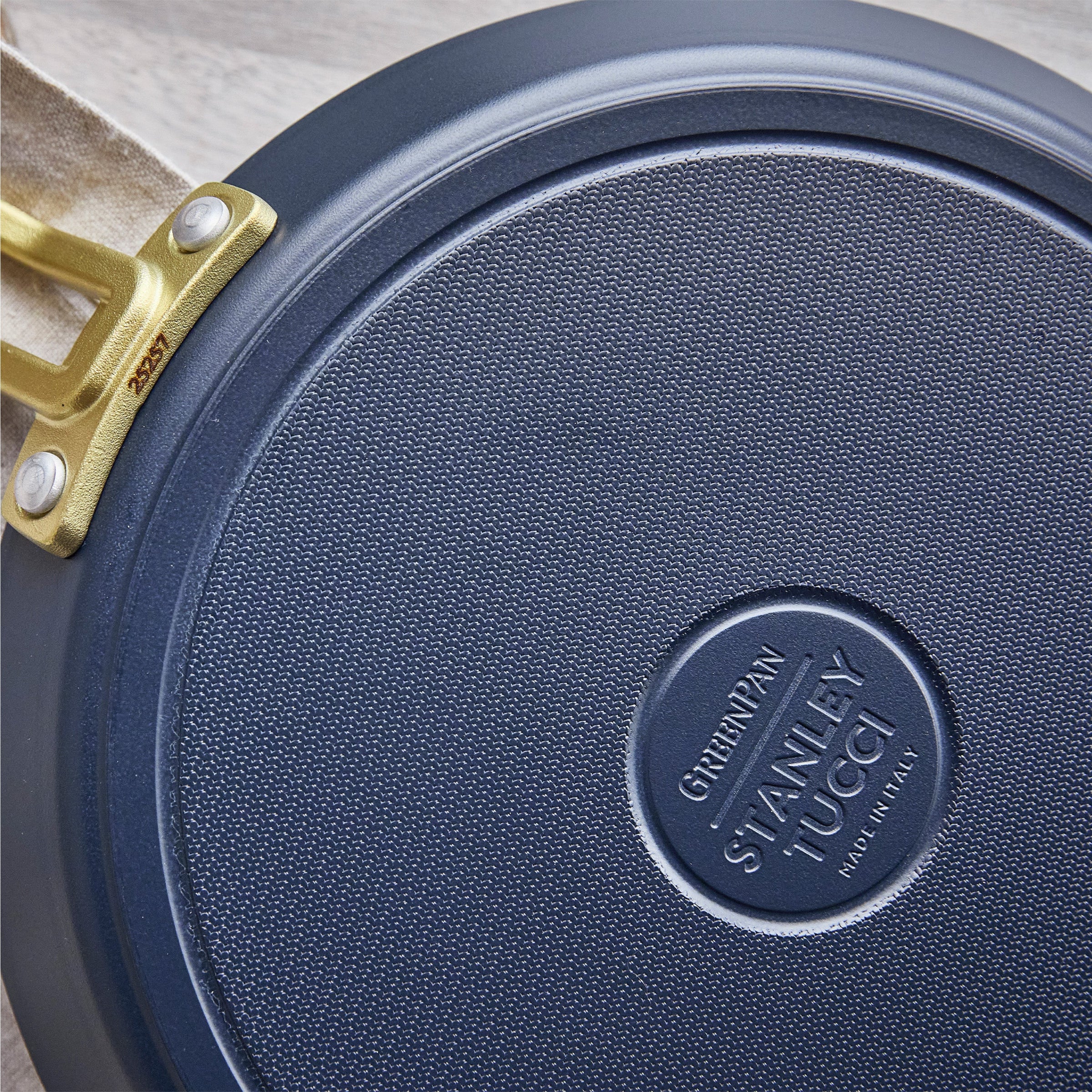 Close-up of a blue crepe pan with 'Stanley Tucci' branding on a wooden surface.