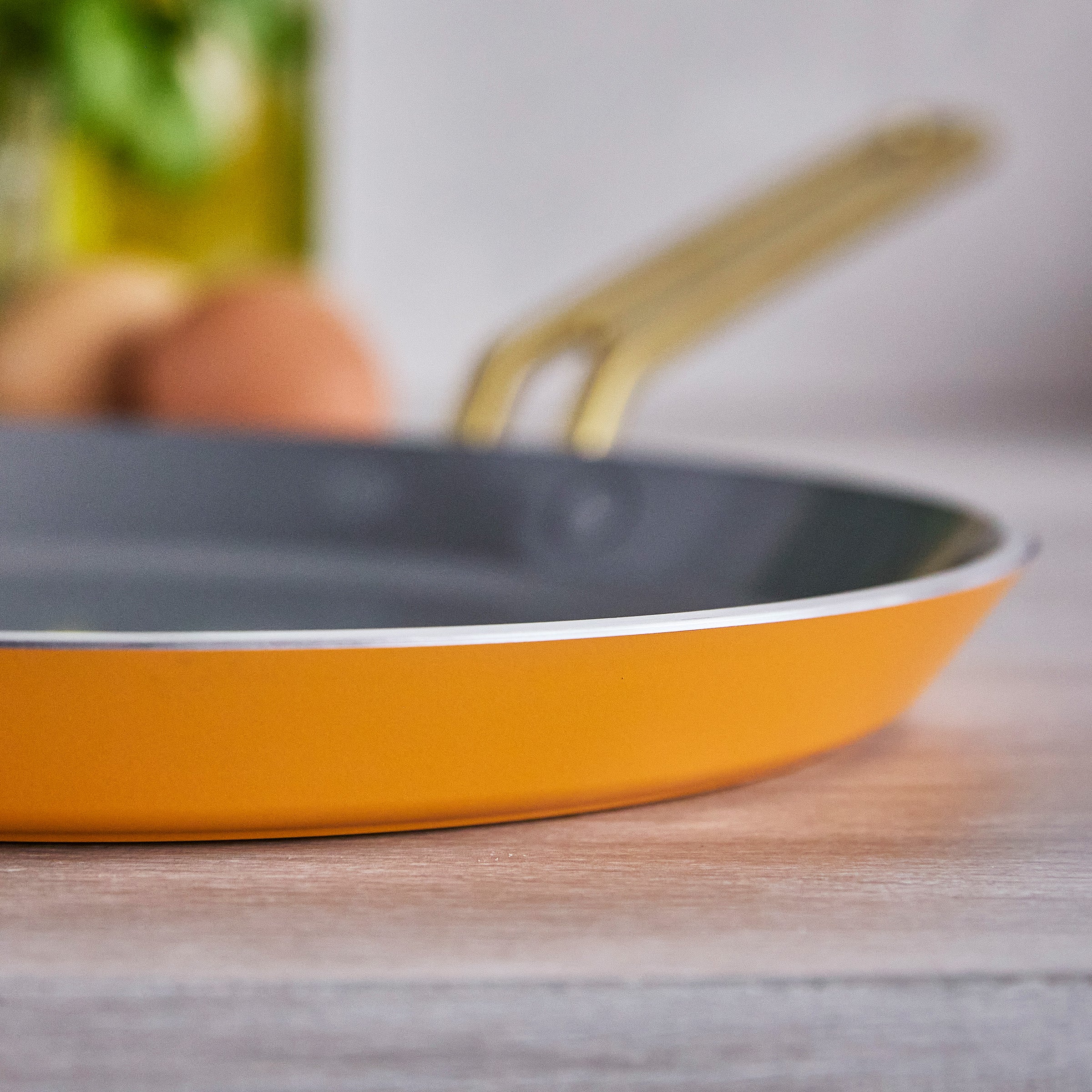 Yellow crepe pan on a wooden surface with a blurred background