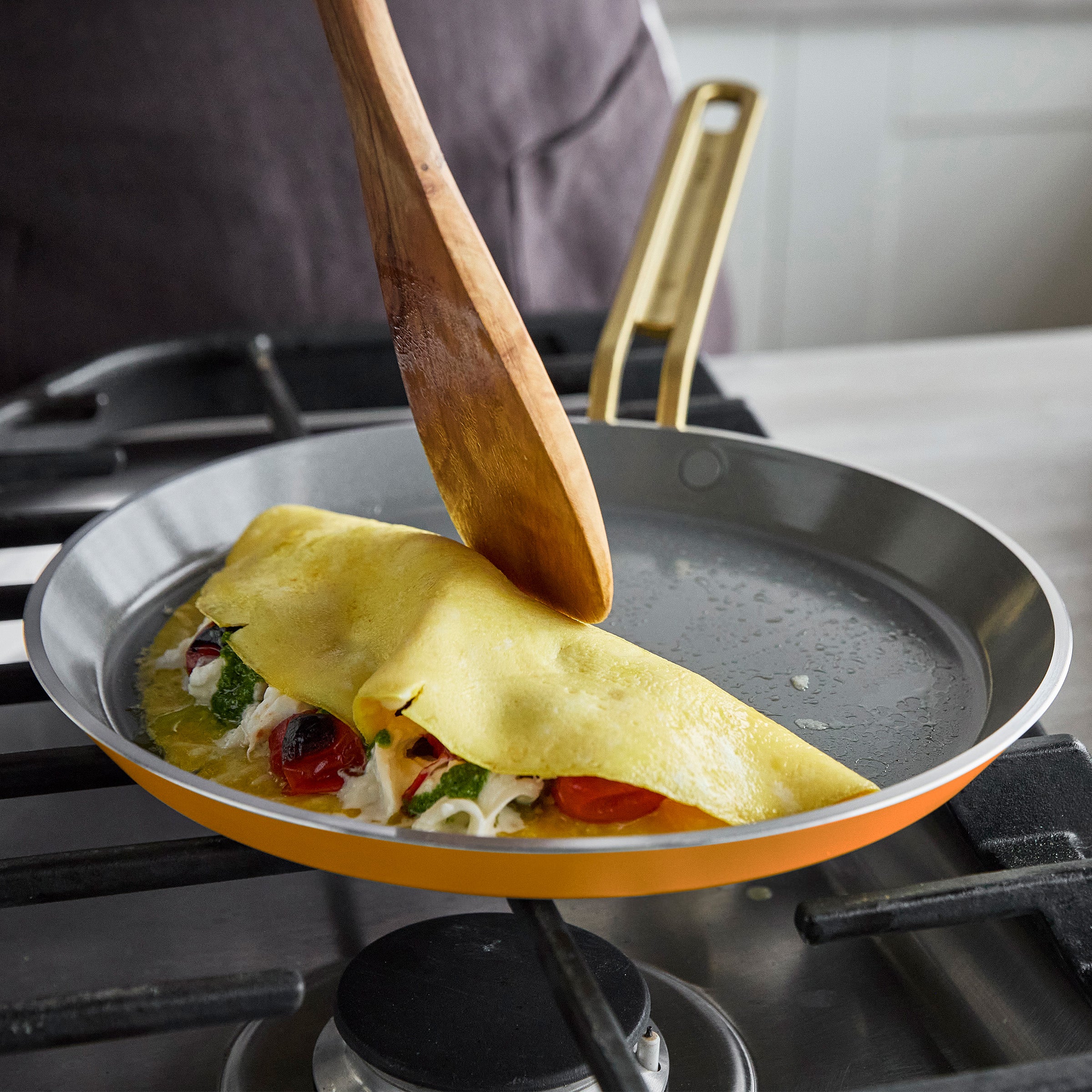 Crepe being folded in a pan with a wooden spatula
