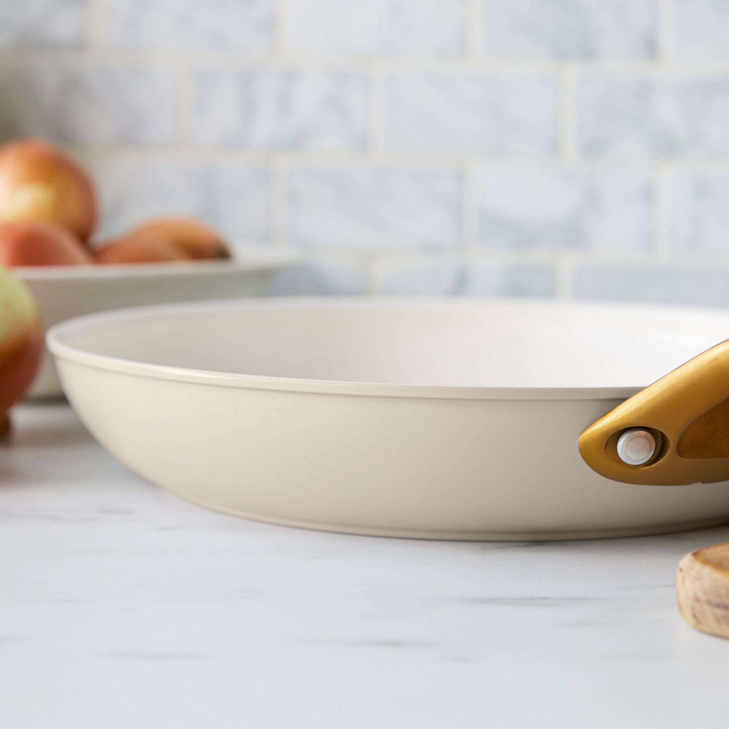 Taupe frying pan with a gold handle on a kitchen counter