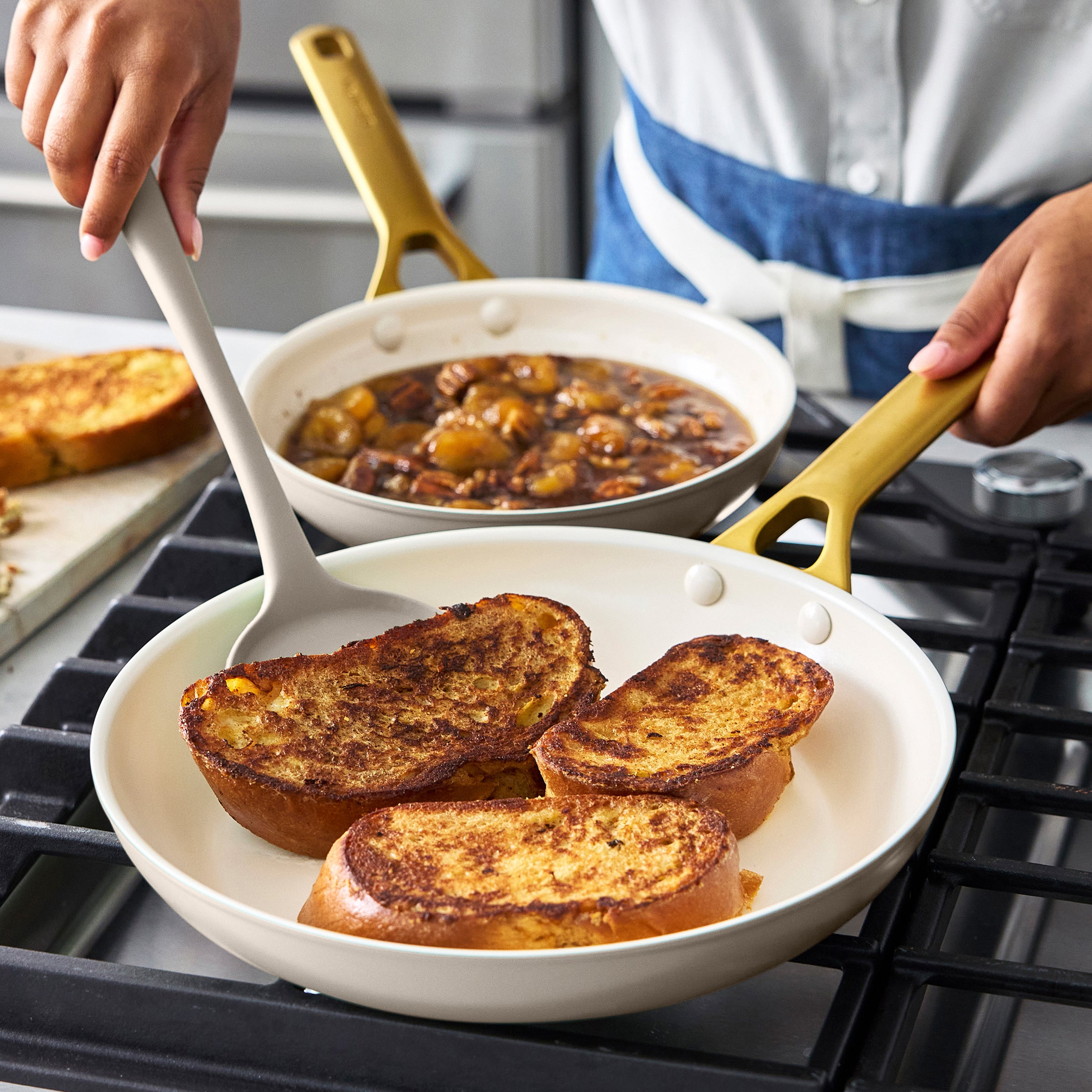 Person cooking French toast in a taupe frypan on a stove.