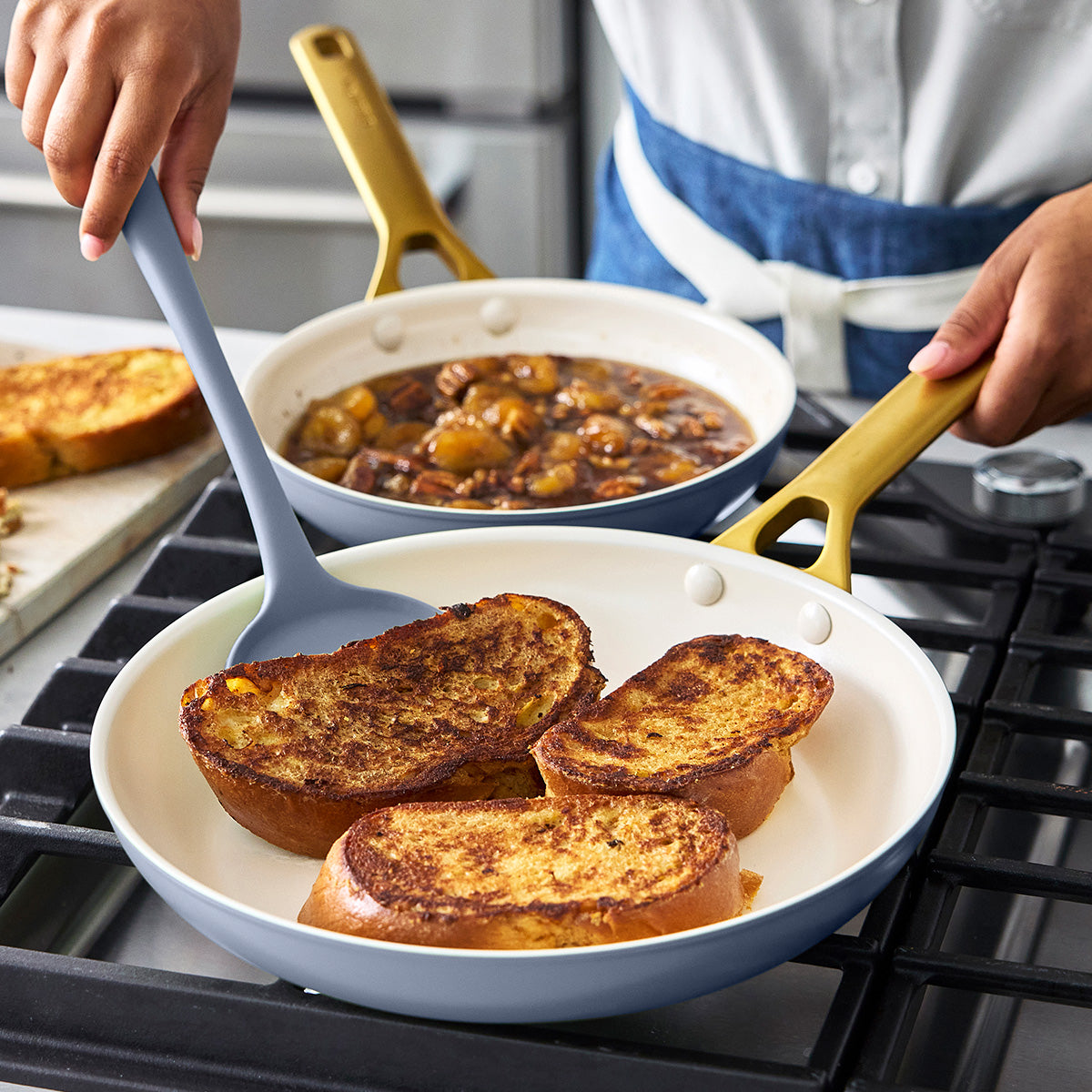 Person cooking French toast in a blue frypan on a stovetop with a blue spatula.