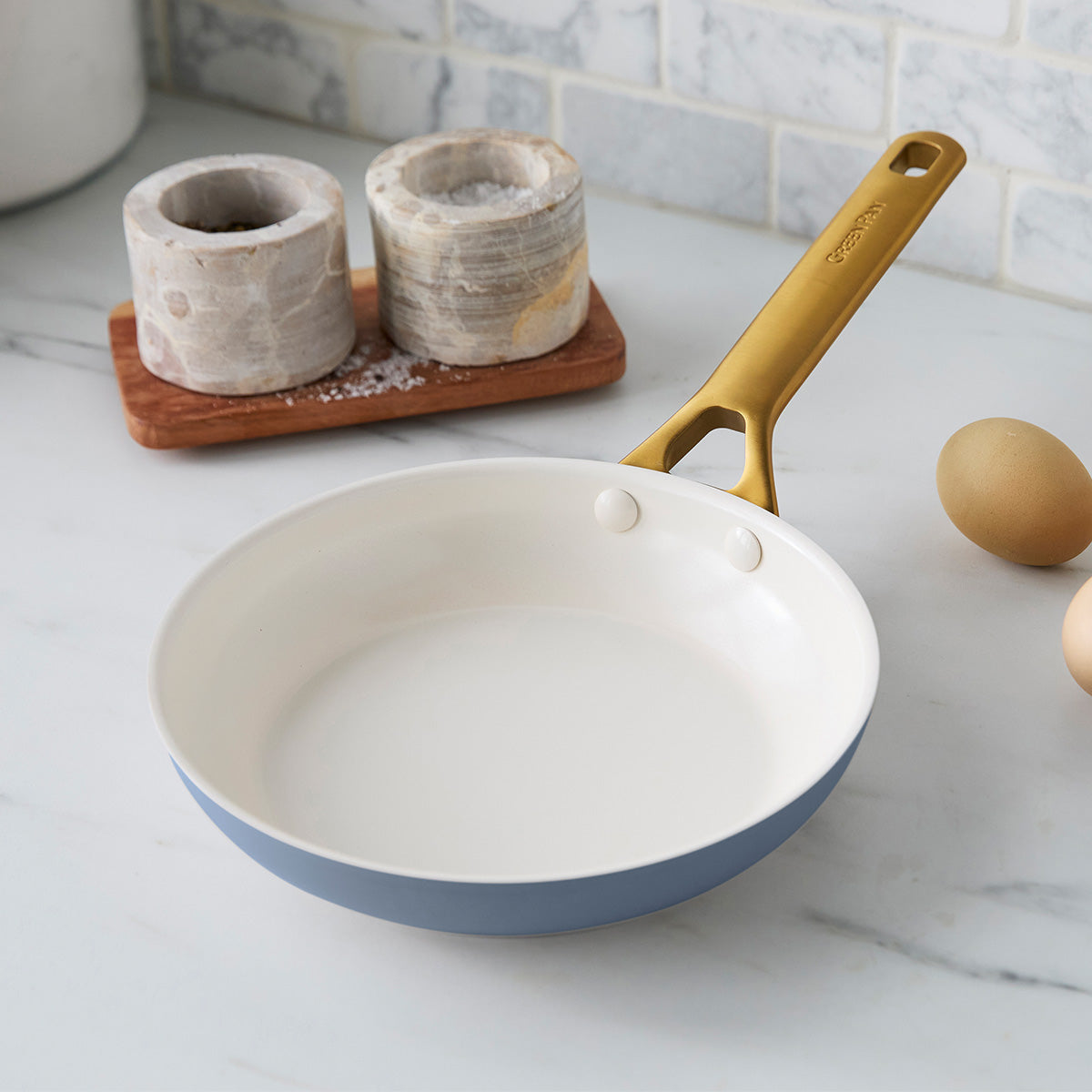 Blue frying pan with gold handle on a kitchen counter