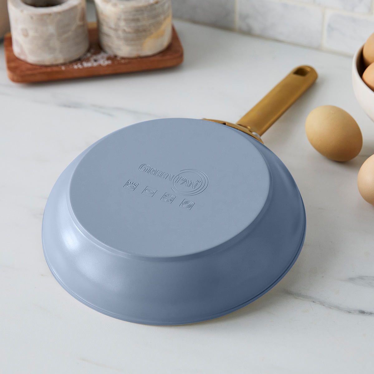 Blue frying pan with a gold handle on a kitchen counter