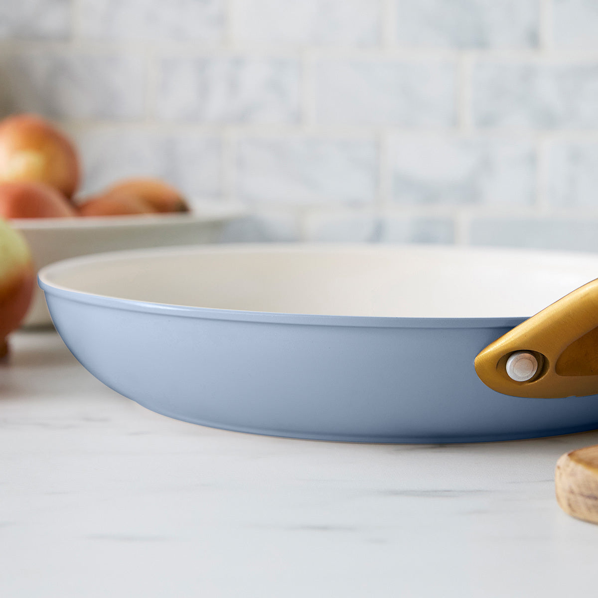 Blue frying pan with a gold handle on a kitchen counter