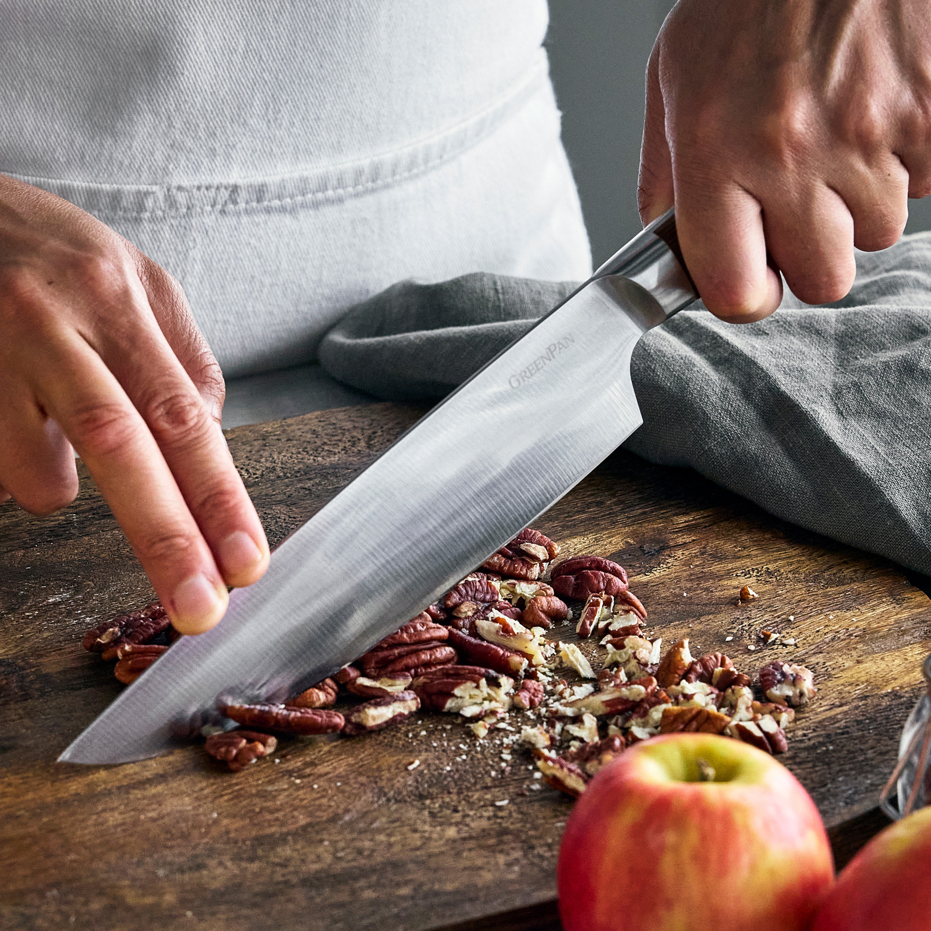 Person chopping pecans on a wooden cutting board with a knife