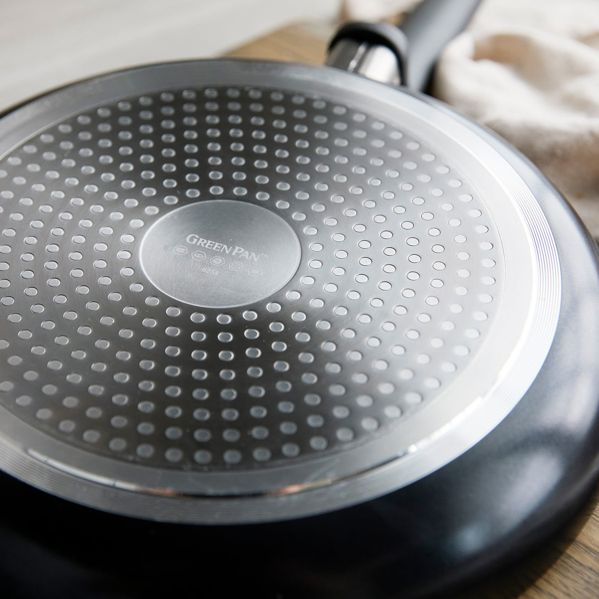 Dotted metal base of 8-inch ceramic frypan with GreenPan logo, shown in close-up.