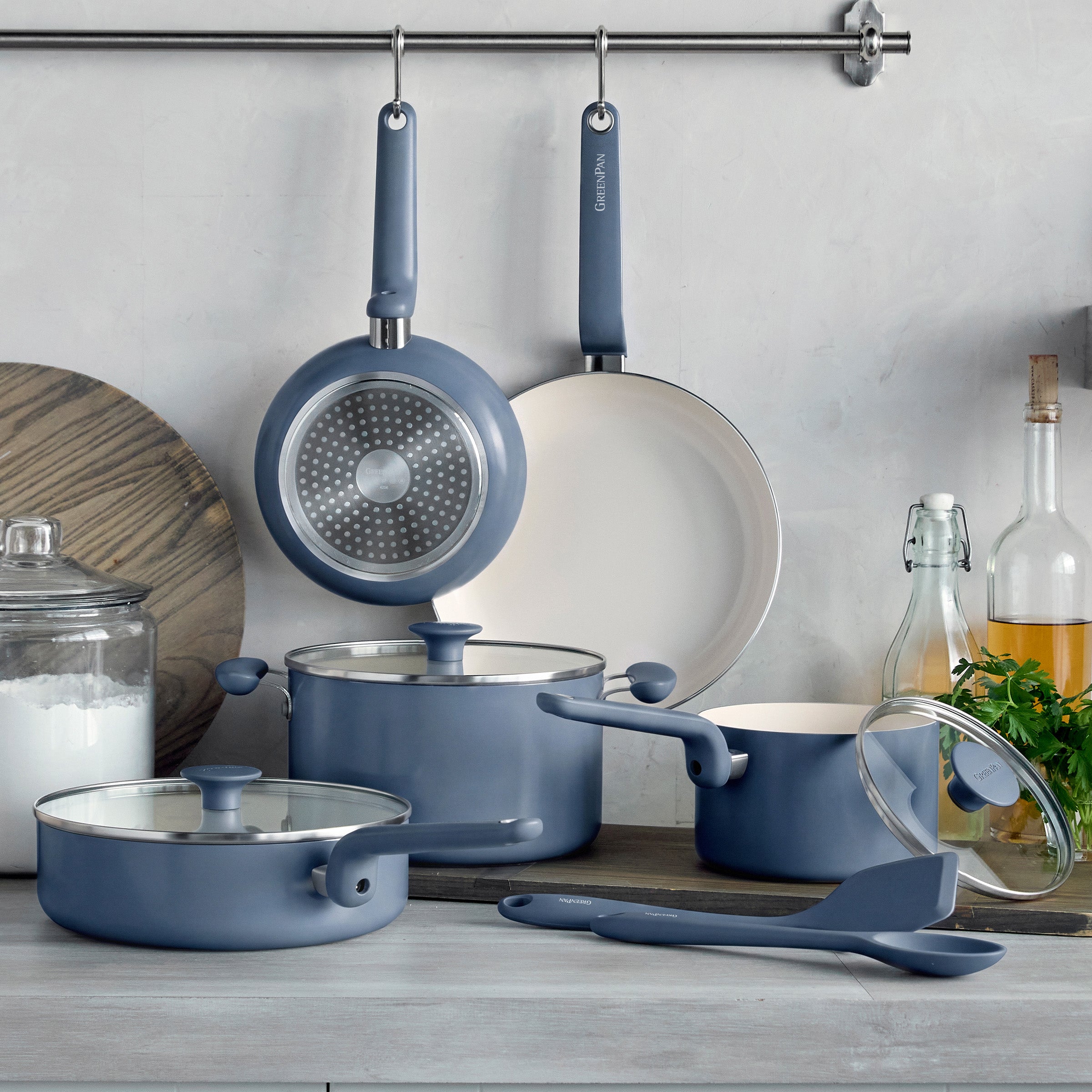 Blue 10-piece ceramic cookware set with pots, pans, lids, utensils, and spices arranged together.