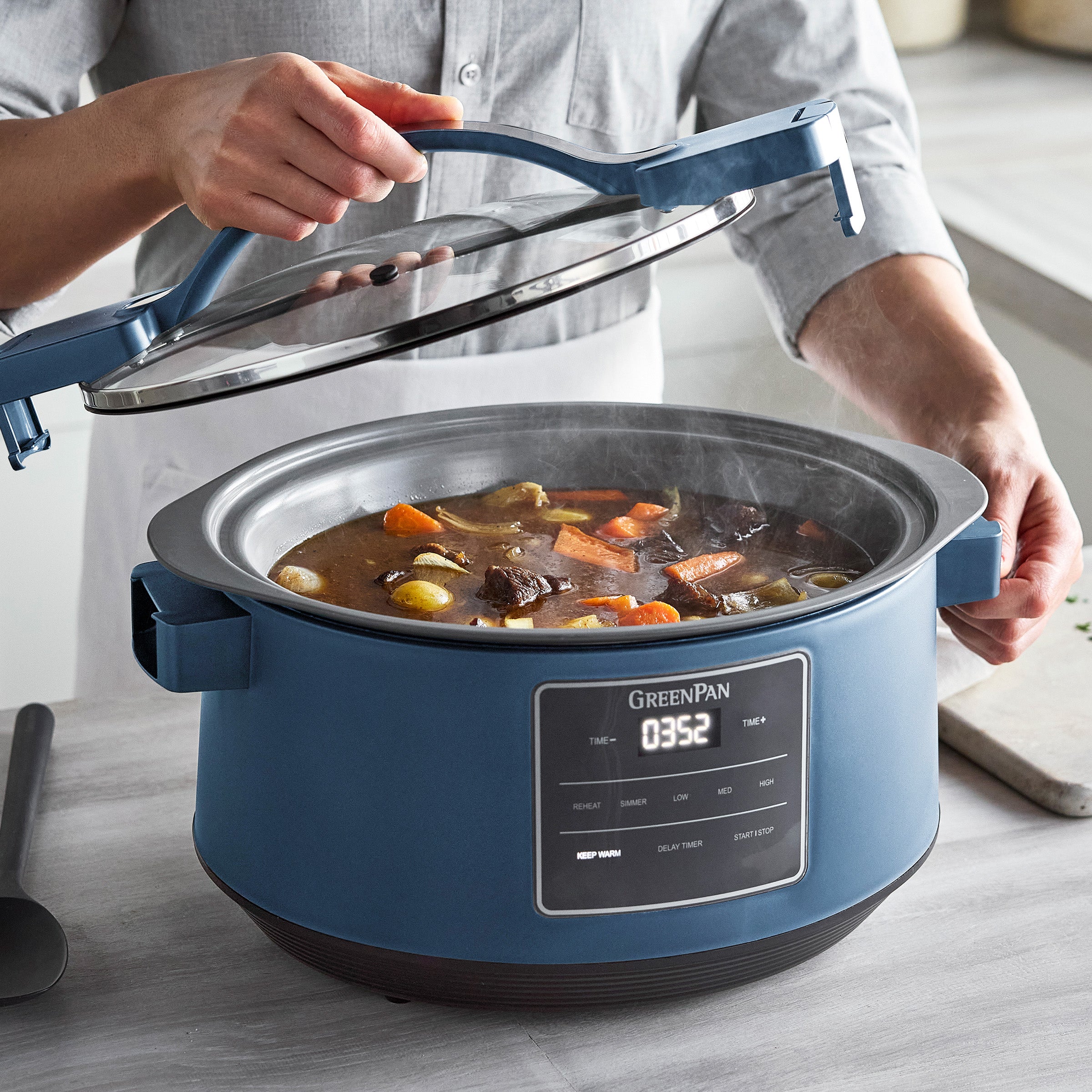 Blue GreenPan slow cooker with a digital display on a kitchen counter, containing a stew.