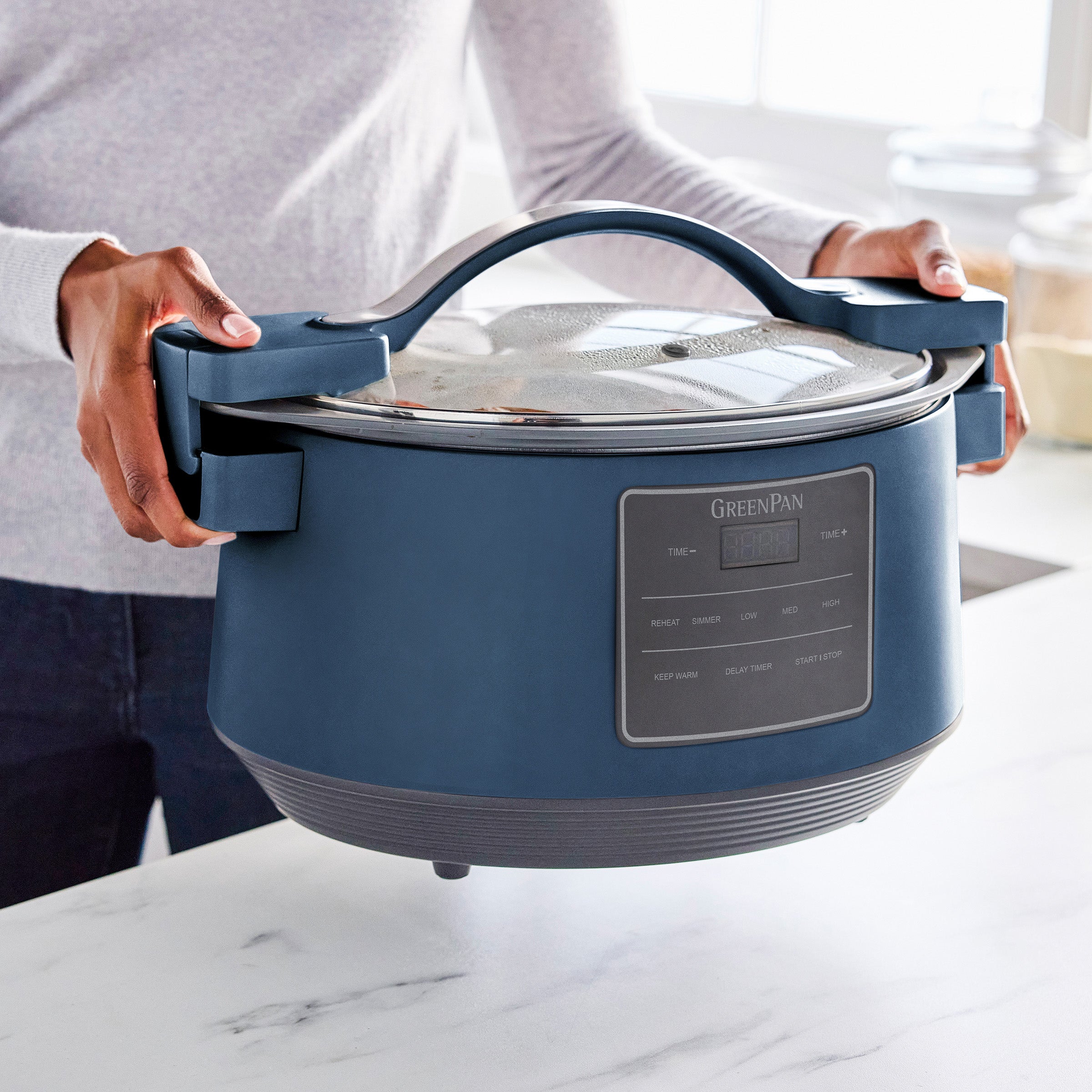 Blue GreenPan slow cooker held by a person in a kitchen setting