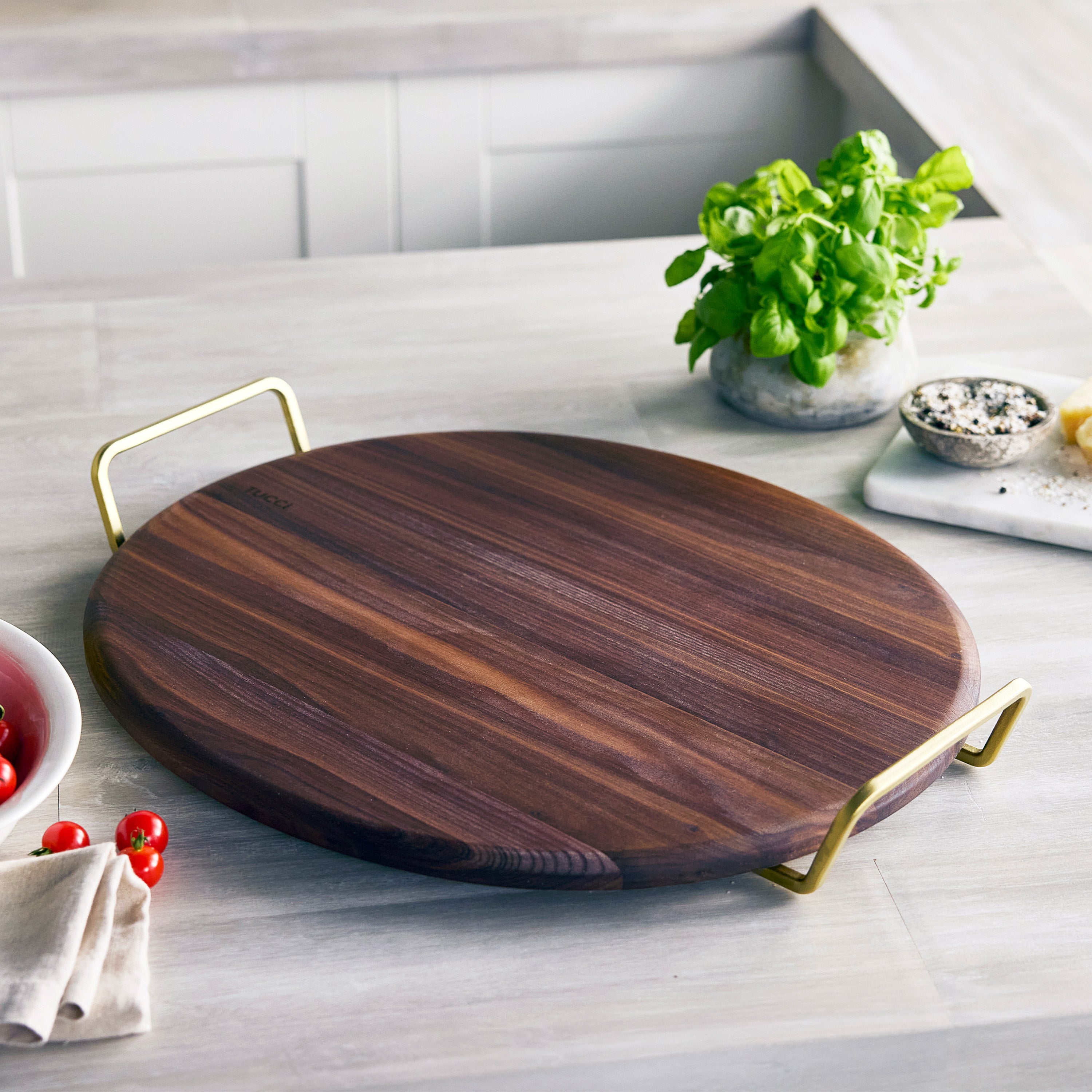 Wooden pizza stone with gold handles on a kitchen counter
