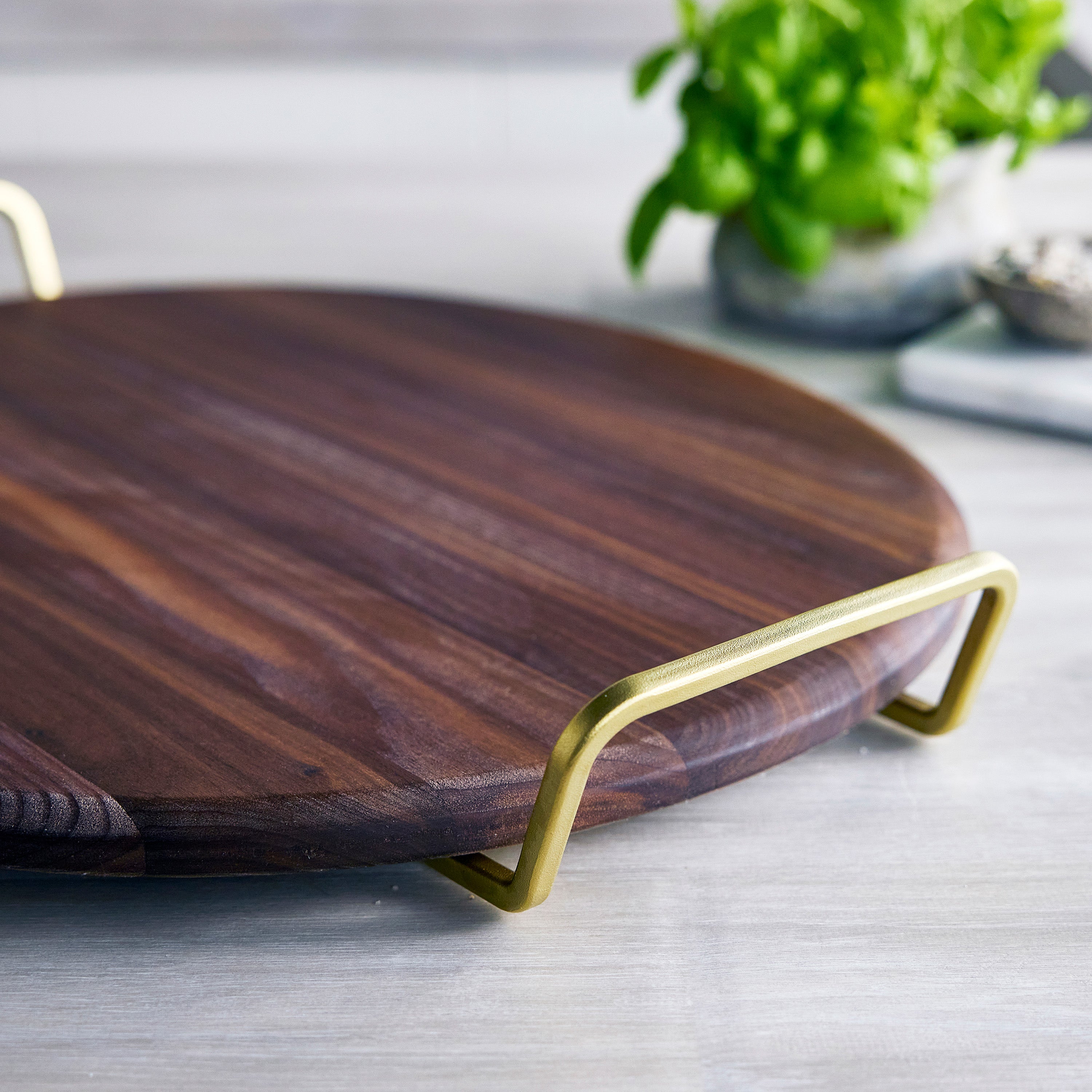 Wooden pizza stone with gold handles on a light surface