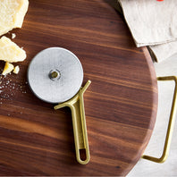 Pizza wheel on a wooden pizza stone with cheese