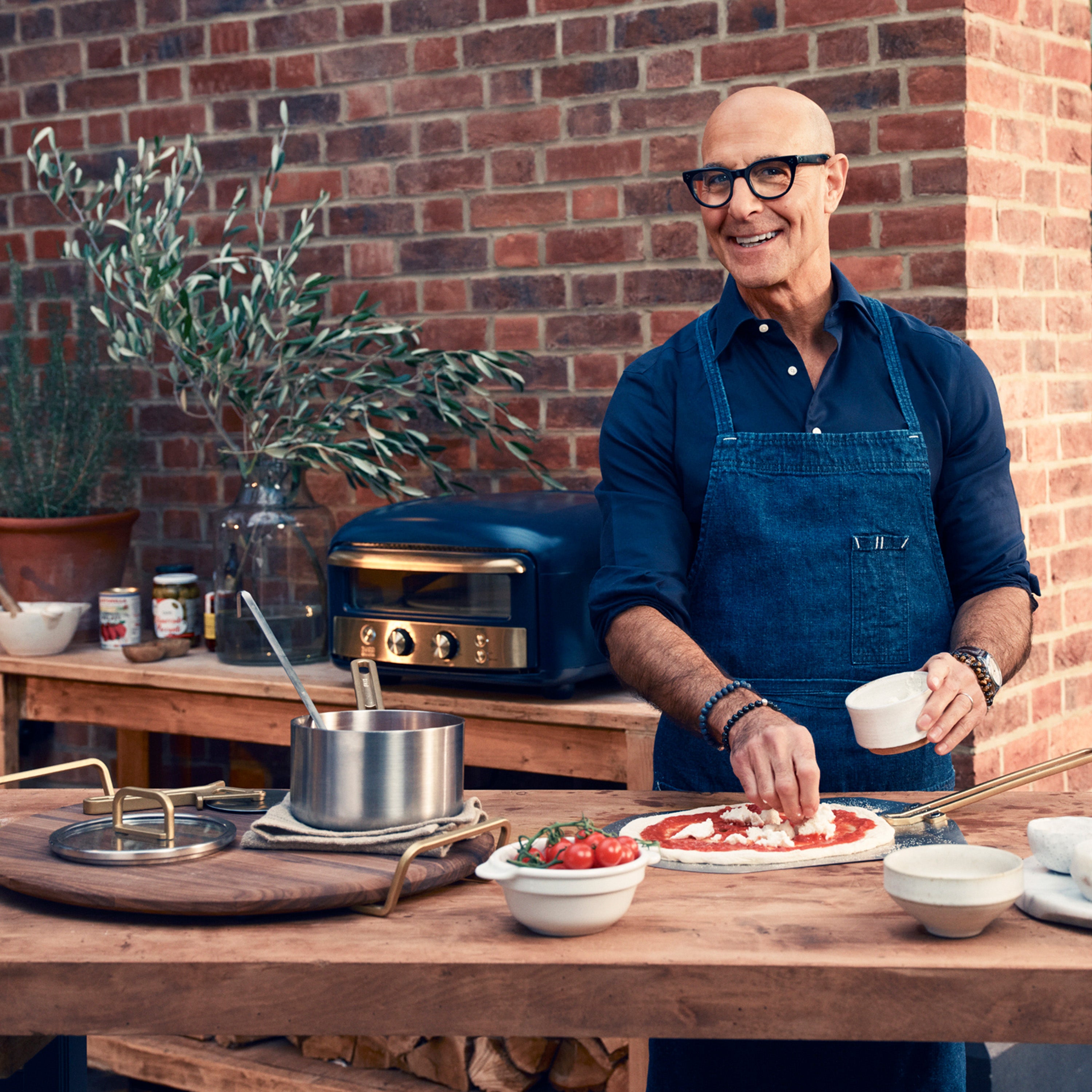 Man preparing food outdoors with a brick wall background