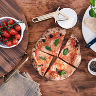 Wooden pizza stone with a small pizza, tomatoes, and a pizza cutter.