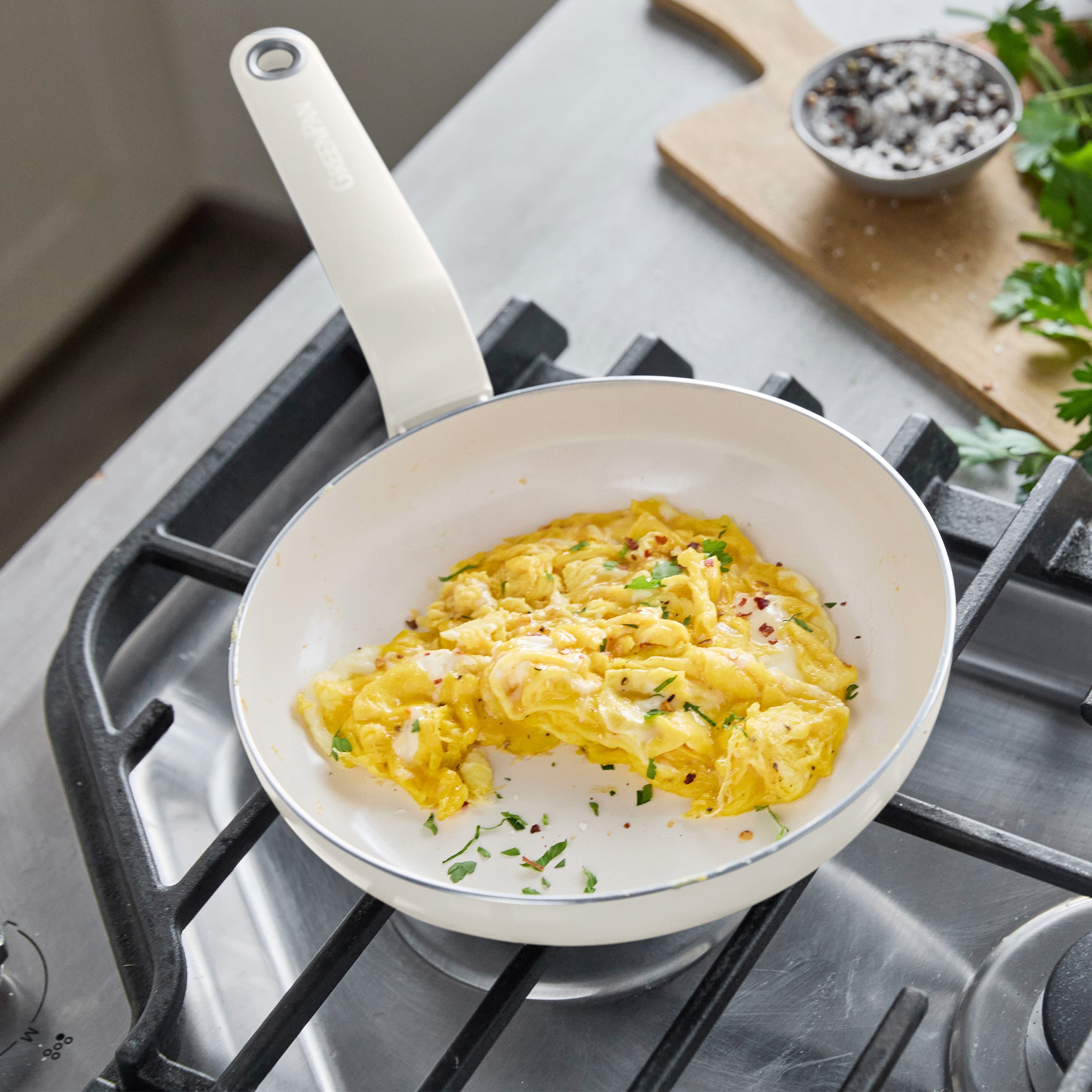 Scrambled eggs with herbs in an 8-inch ceramic nonstick frypan, with small bowls of cream, salt, and parsley on the side.