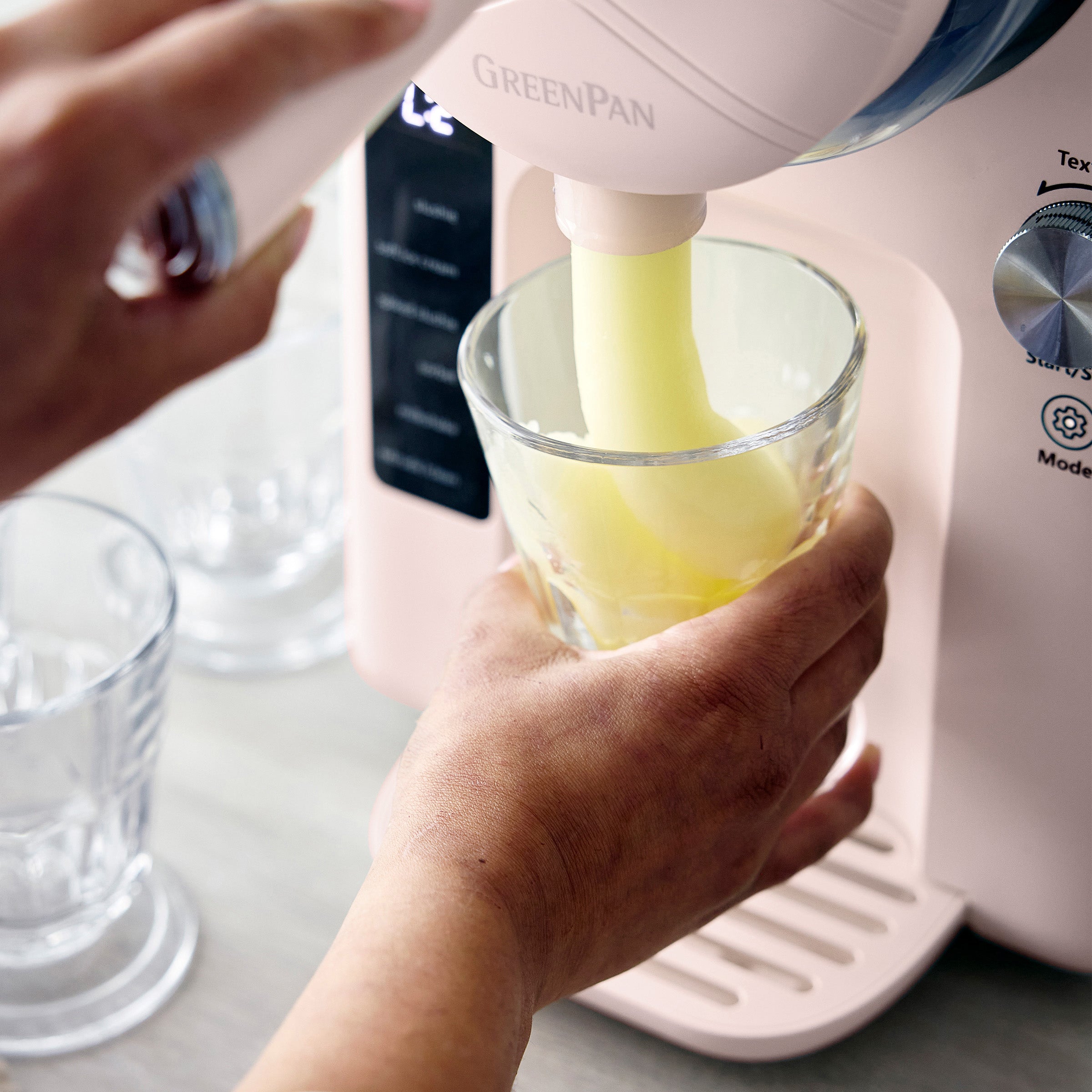Person pouring a frozen margarita from a pink kitchen appliance into a glass