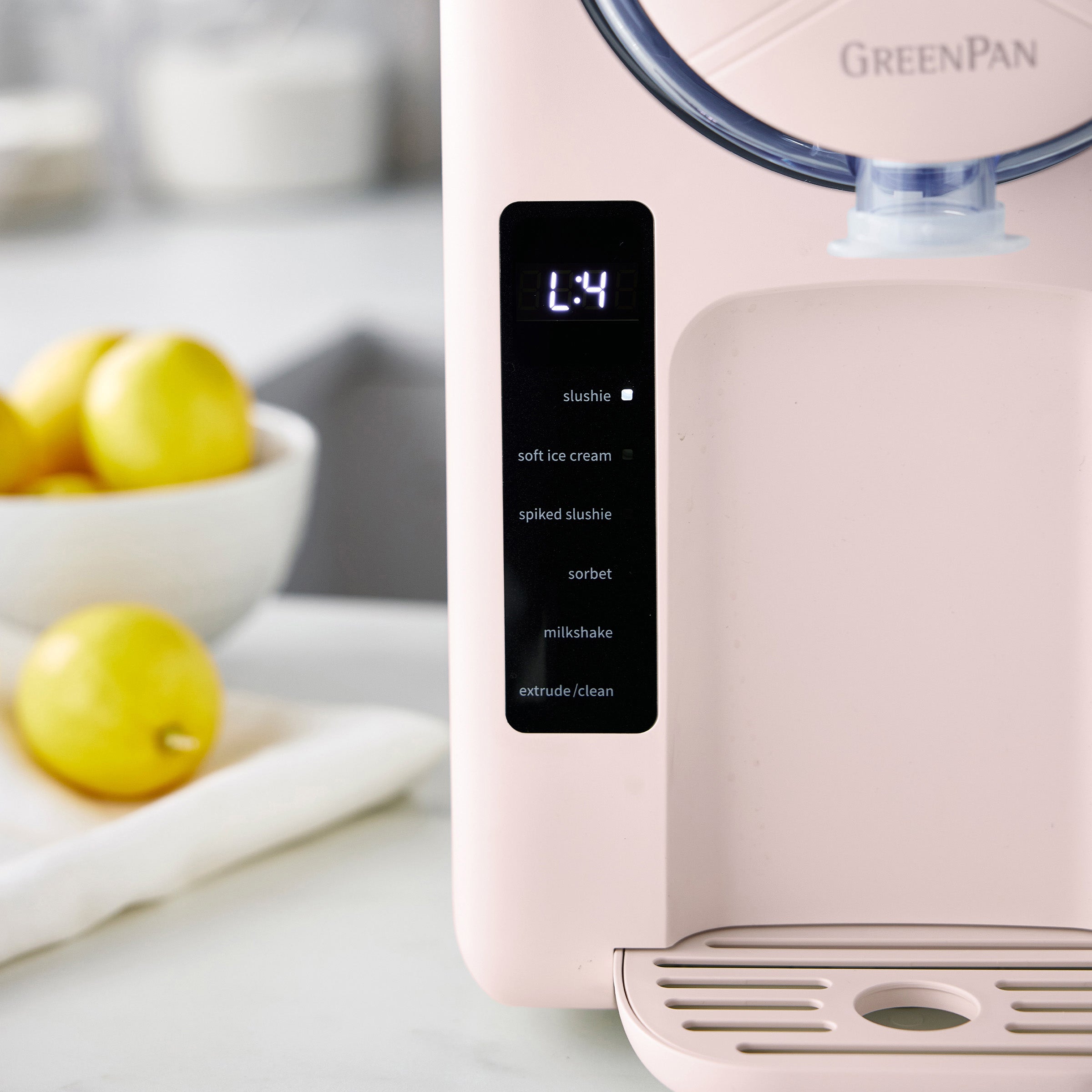 Pink ice cream maker with digital display on a kitchen counter, surrounded by lemons.