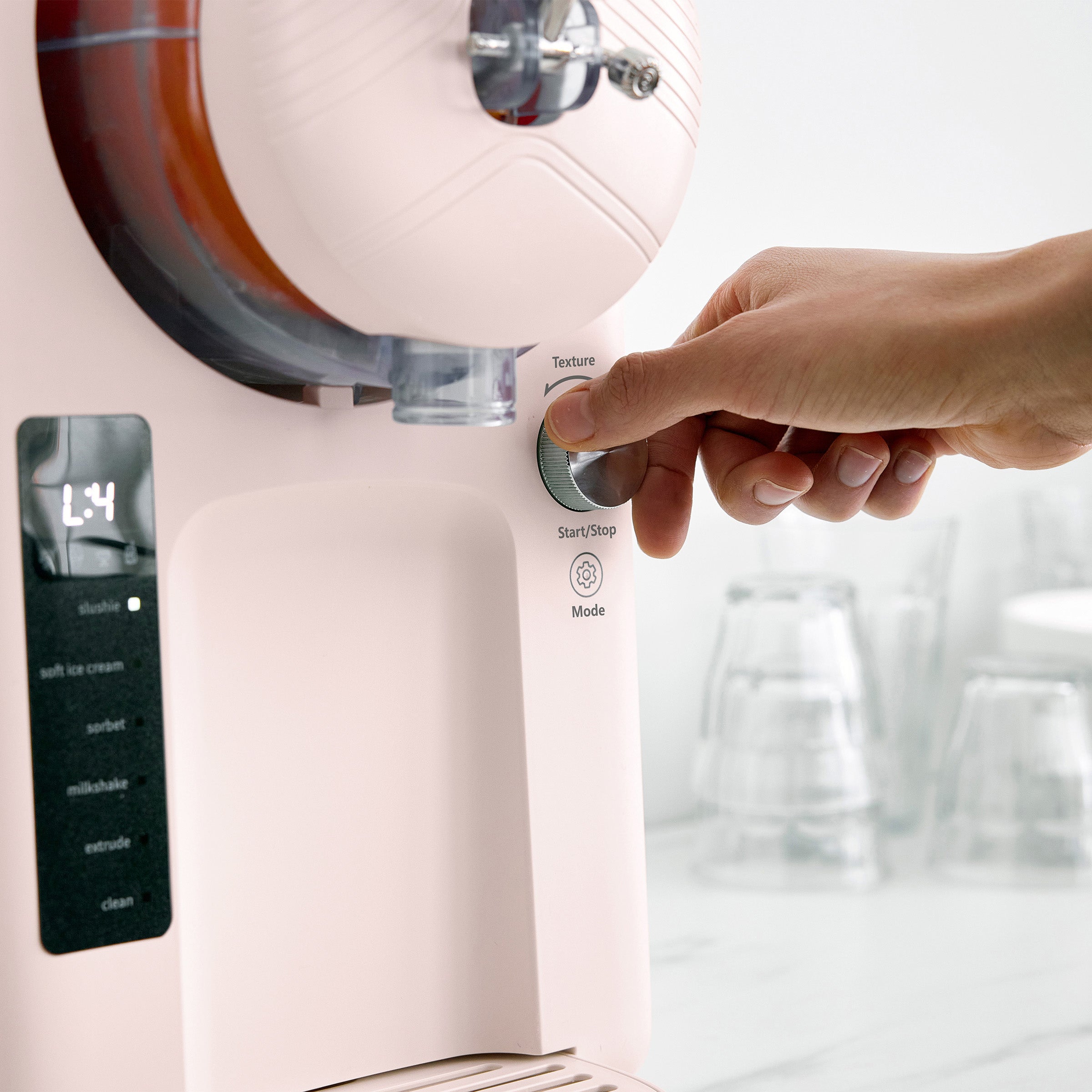 Hand pressing a button on a pink ice cream machine with a blurred background