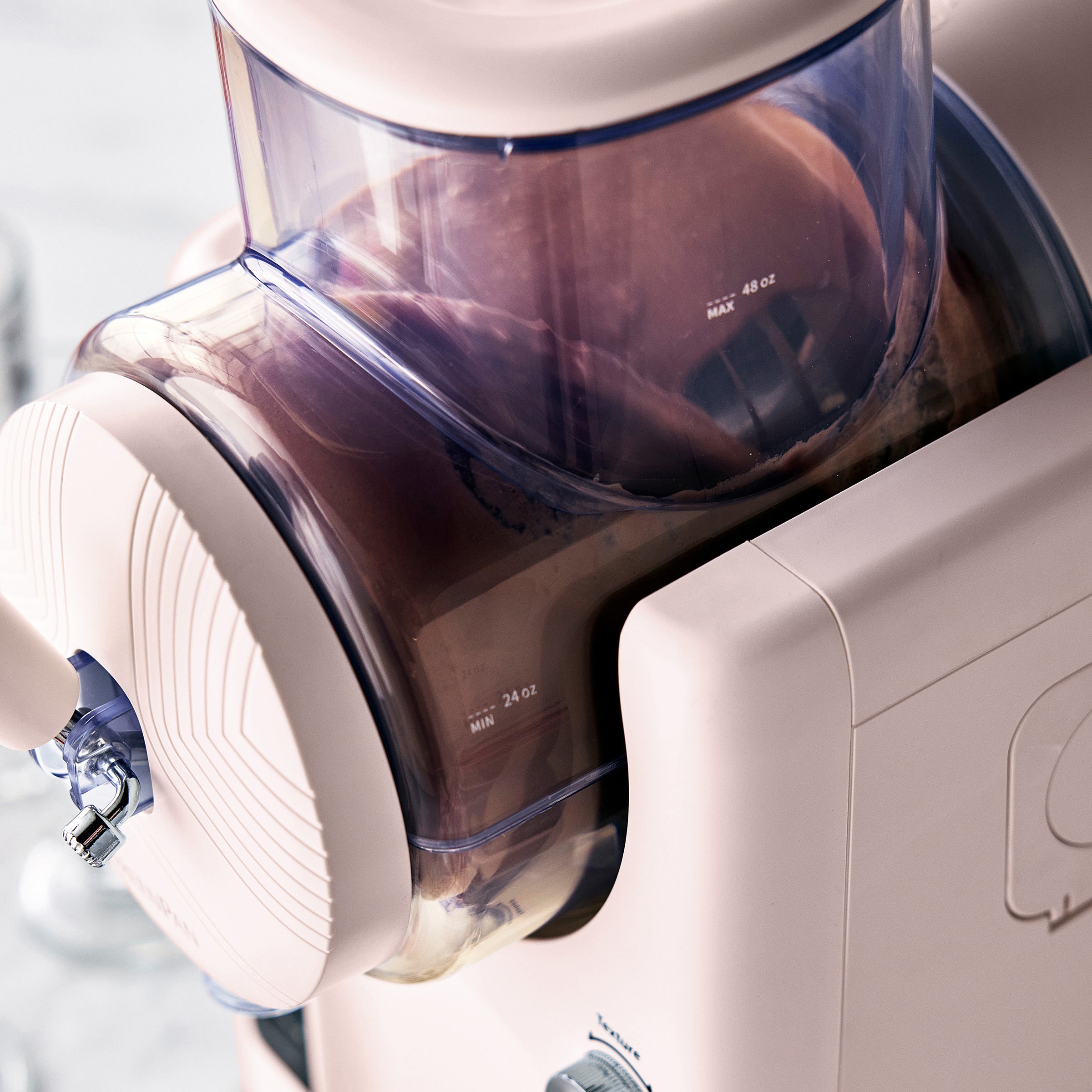 Close-up of a pink ice cream maker with a clear container filled with chocolate ice cream