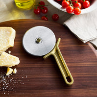 Pizza cutter on a wooden board with cheese and tomatoes in the background