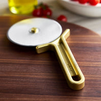 Gold pizza cutter on a wooden surface with blurred background
