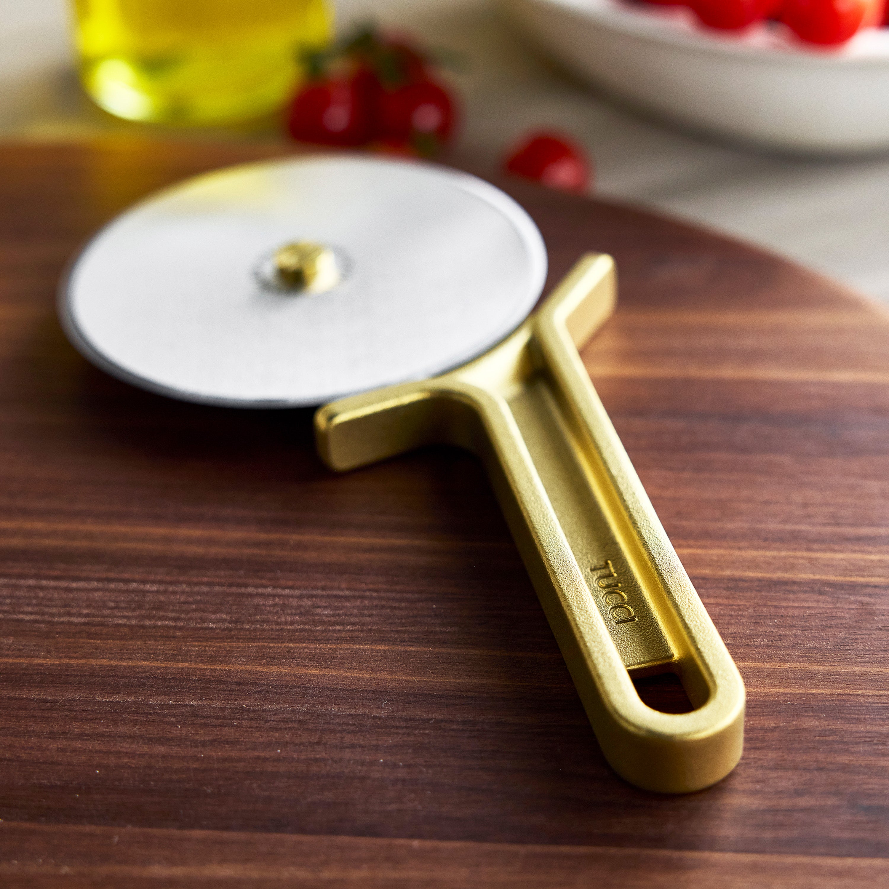 Gold pizza cutter on a wooden surface with blurred background