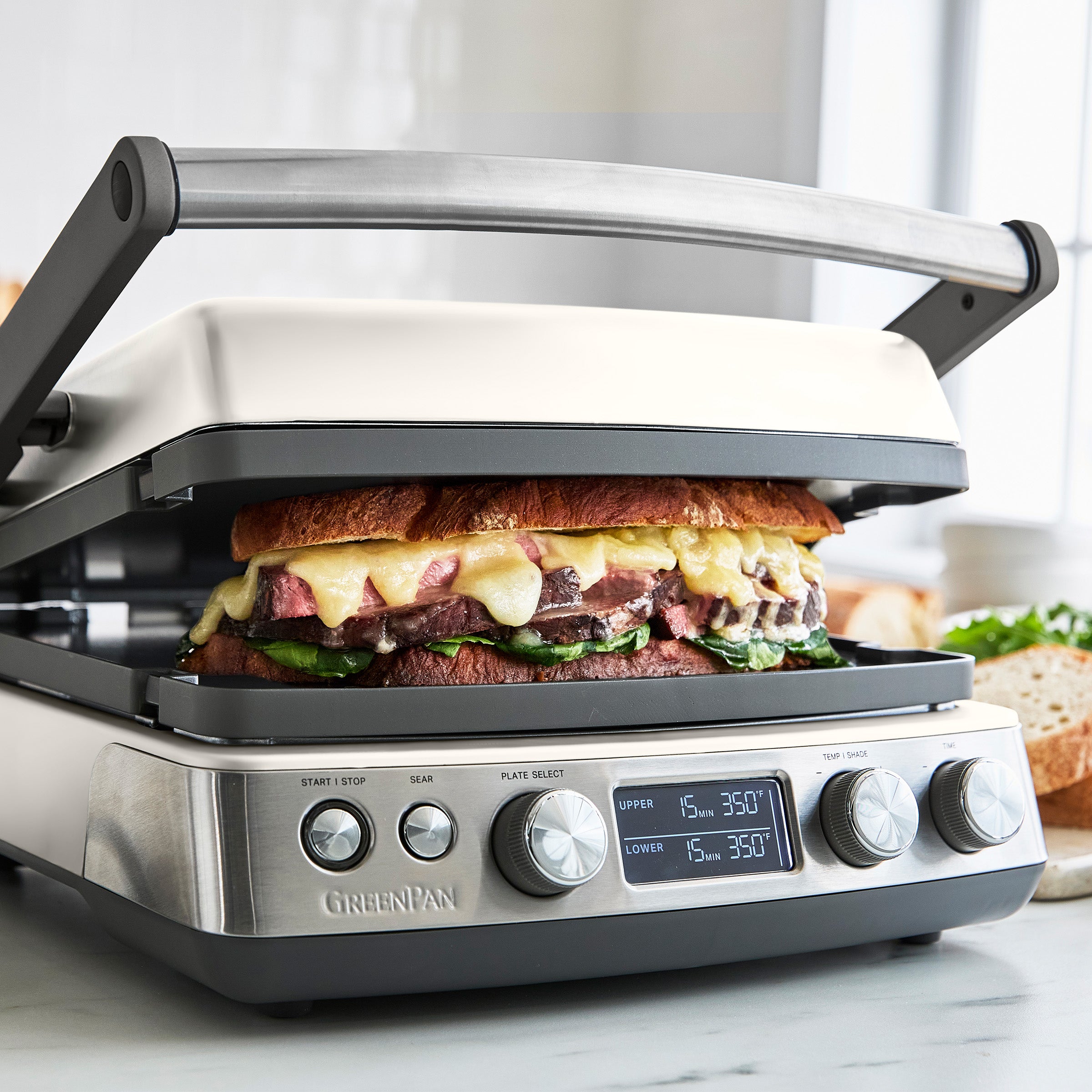Sandwich in a panini press with digital display on a marble countertop.