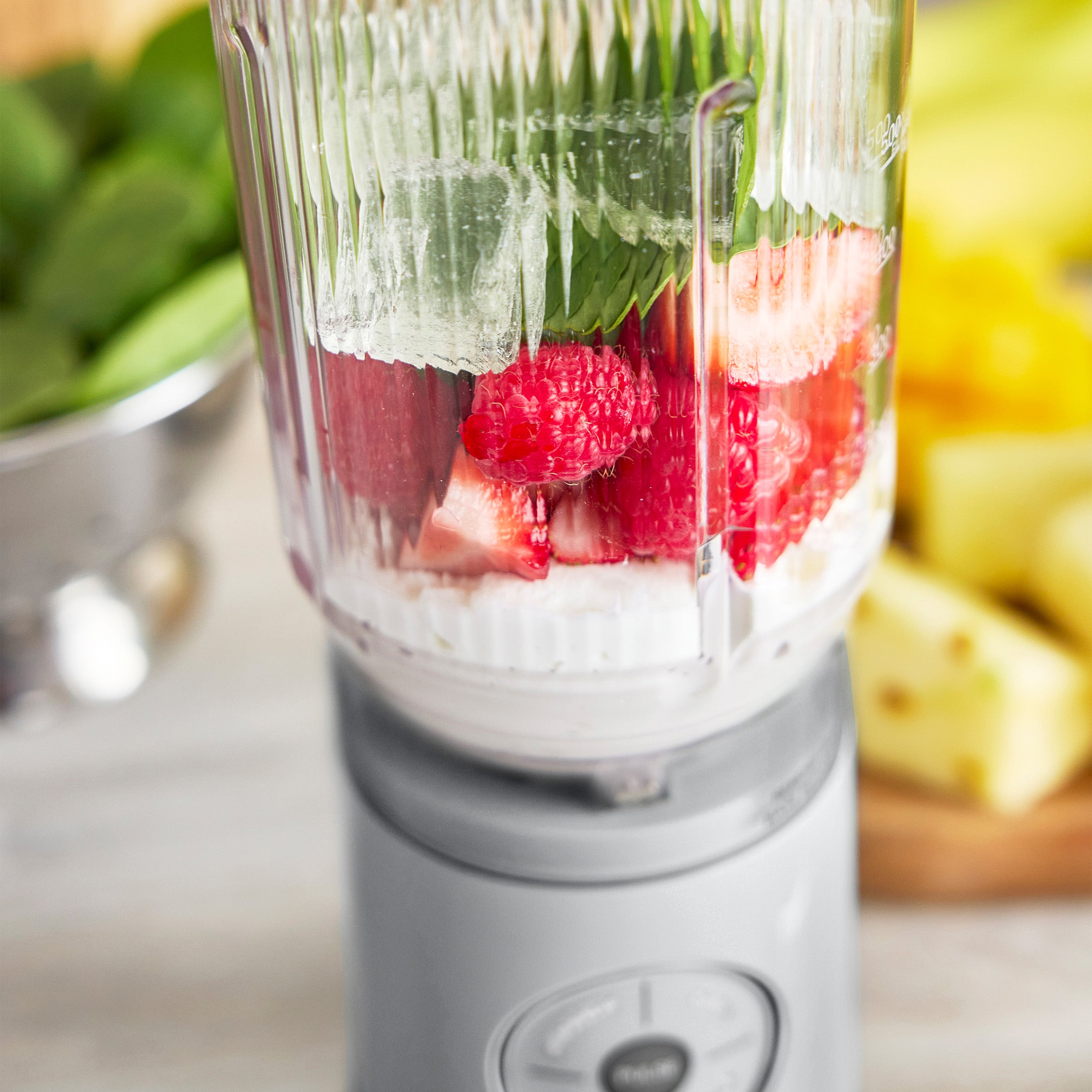 Blender with fruits and vegetables on a kitchen counter